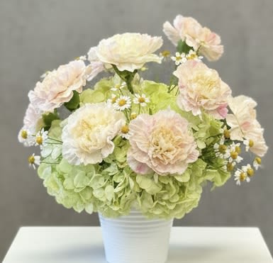 Pastel flower arrangement in a white pot with pale pink blooms and green hydrangeas