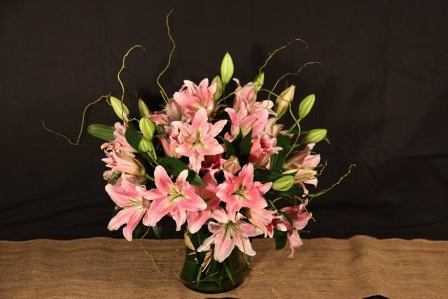 Pink lilies arranged in a glass vase with unopened buds