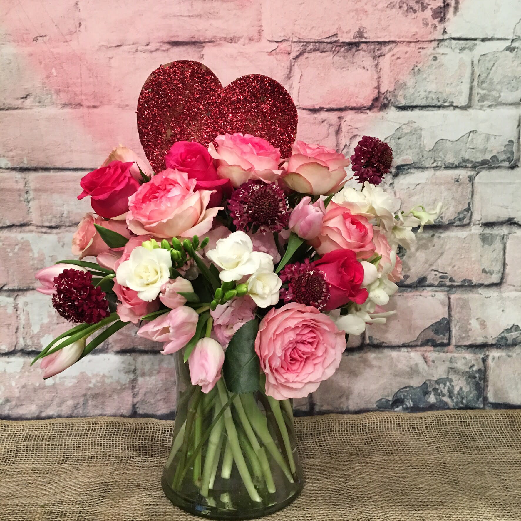 SPARKLE TO YOUR VALENTINE'S - SPARKLE IN A SWEET ASSORTMENT OF LIGHT PINK ROSES, WHITE FREESIA, LIGHT PINK TULIPS, HOT PINK ROSES LIGHT PINK HYDRANGEA, ACCENTED WITH BURGUNDY ESCAVIOSA.