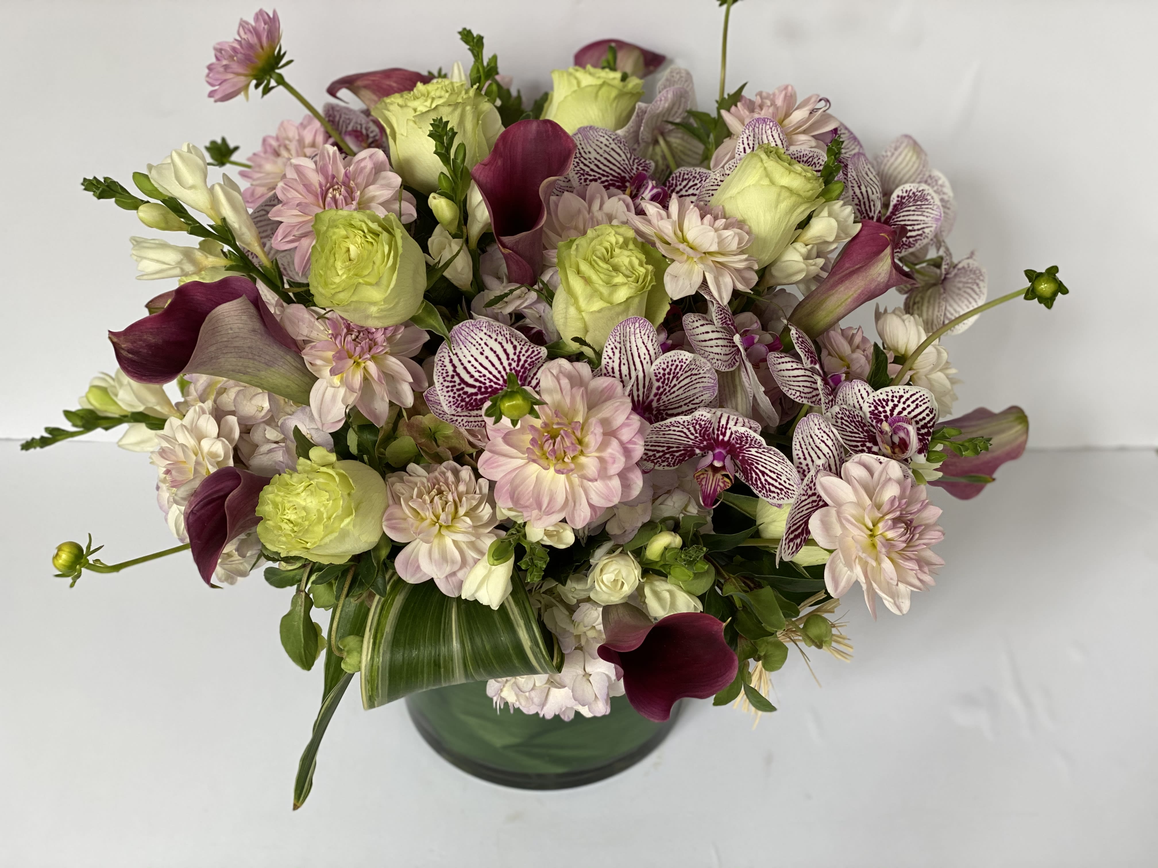 Mixed bouquet of pale pink and green flowers in a glass vase