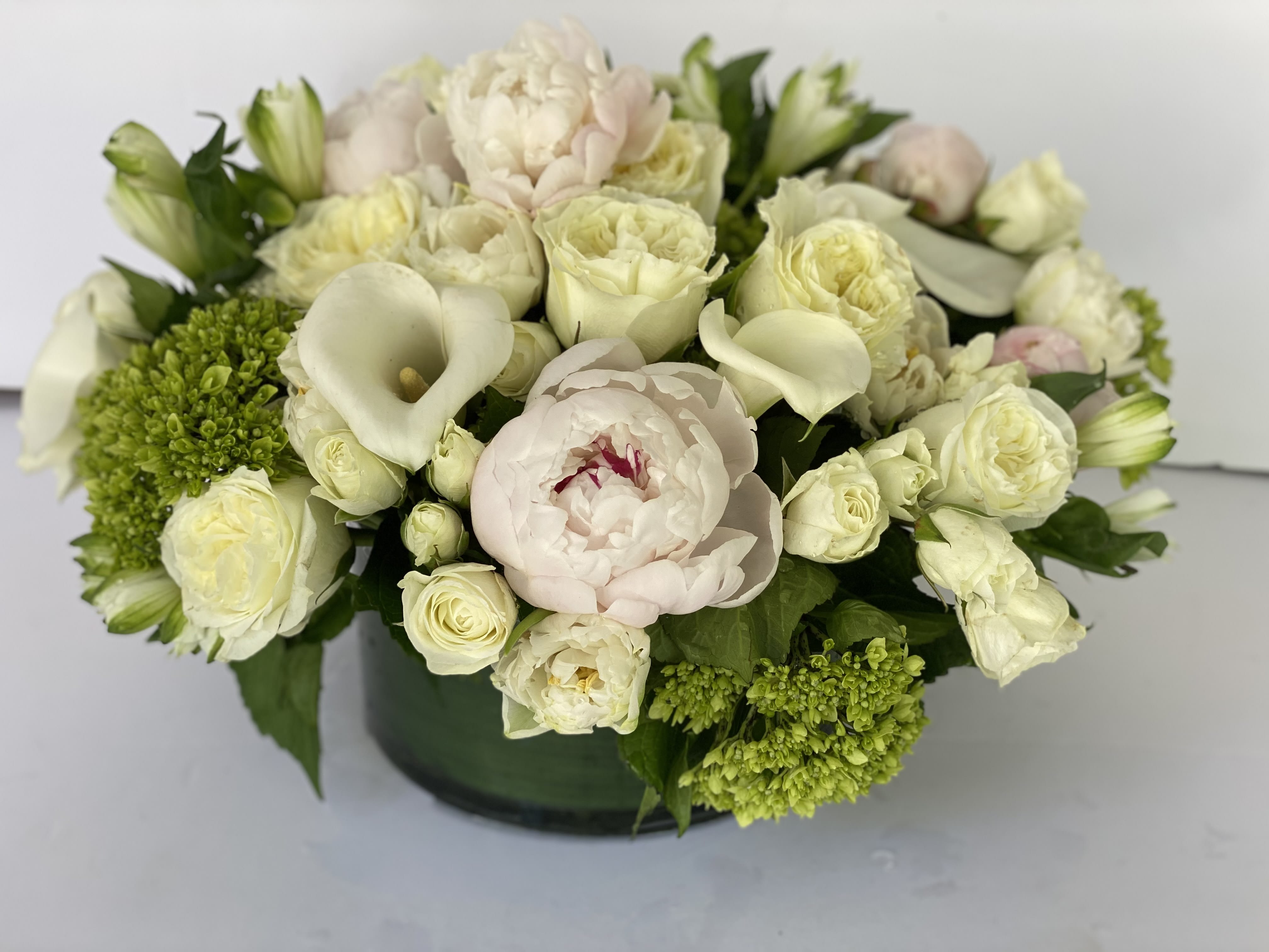 Cream and pale pink floral arrangement in a dark vase