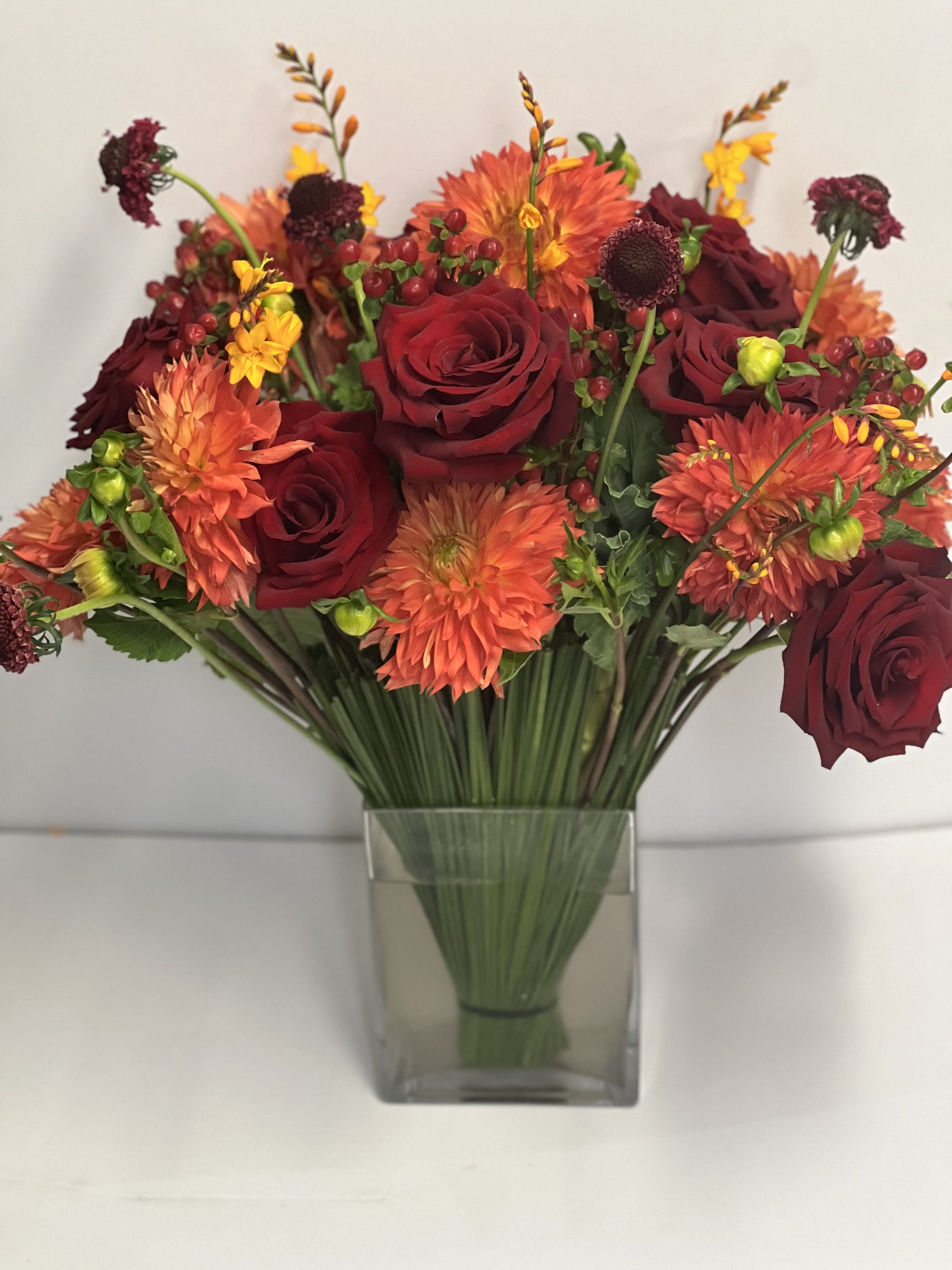 "Broadway" - Lush assortment of long stemmed flowers set in a cluster of steel grass from Australia, surrounded by large heads mango color dahlias, tuck in with kale, explorer roses, buttery color crocosmia, and bicolor scabiosa flower 
