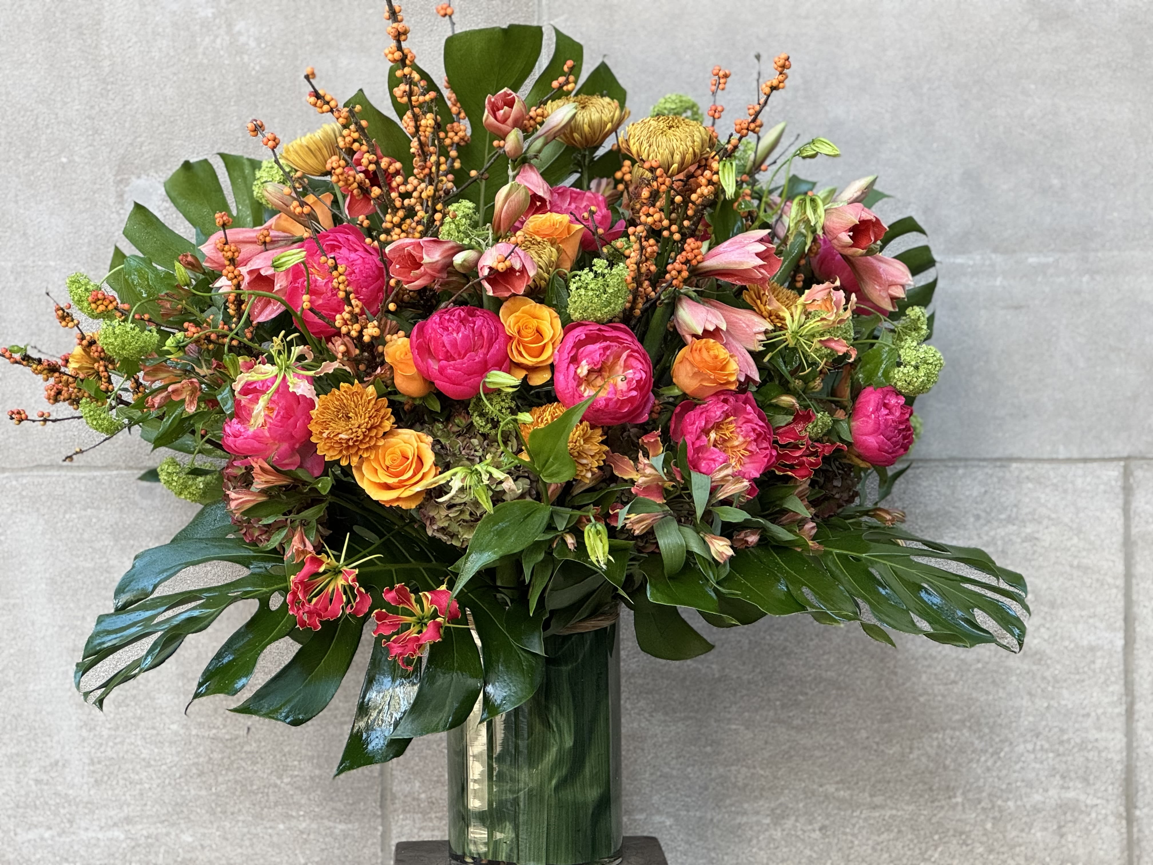 BLISS - For the discerning connoisseur, this extravagant, seasonal assortment of coral charm peonies, amaryllis Naranja, orange ilex berries, tycoon roses, snowball viburnums is sure to please those that prefer a high class, refined look.  This design could be custom made in a low profile arrangement or medium height display.  Shown is a 48" H x 48" W arrangement. Be the envy of your holiday engagement!