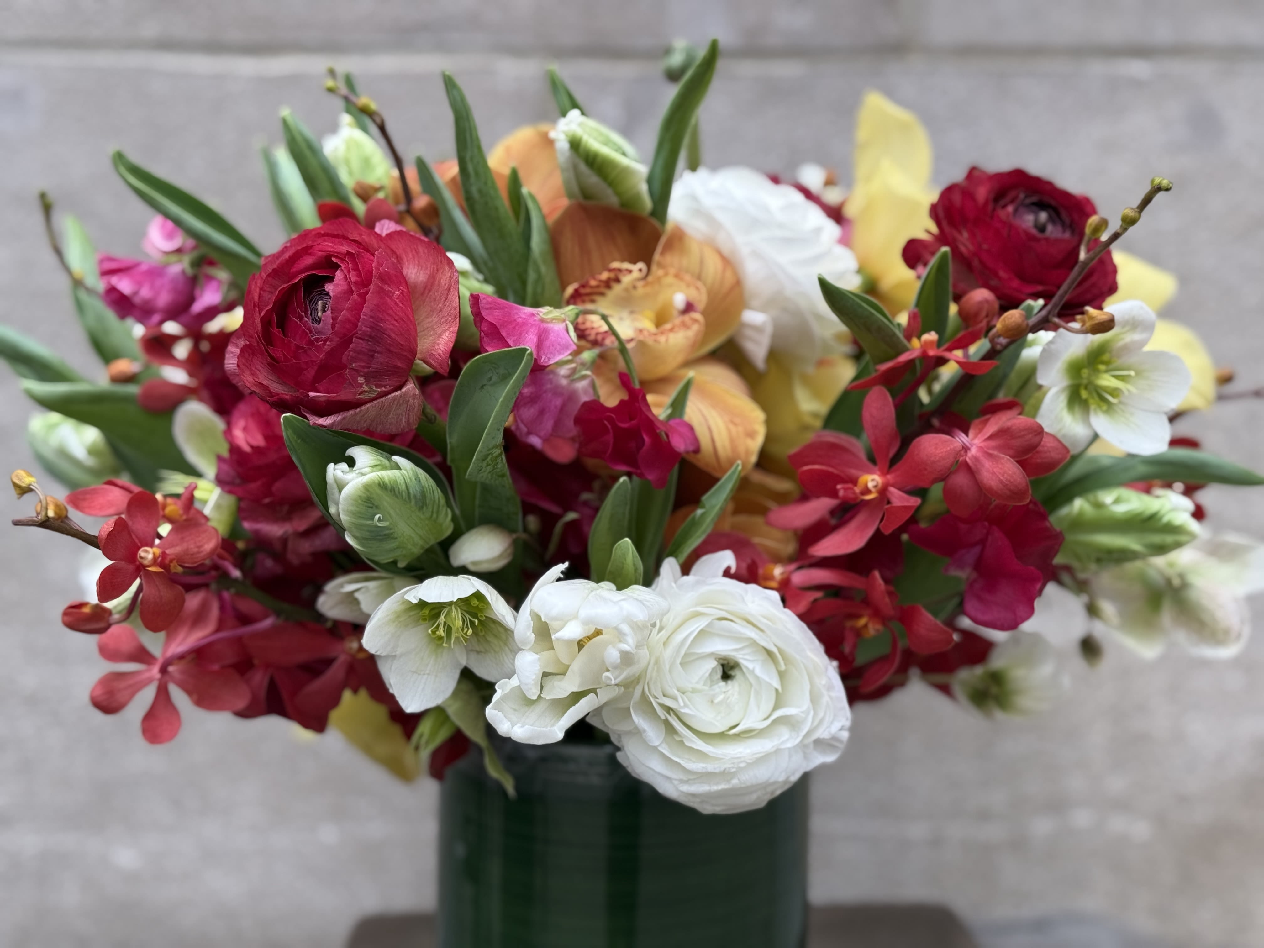“Here, There And Everywhere” - A low and plump arrangement that’s bursting with stunning white and hot pink ranunculus—like springtime decided to throw a party! It’s all cozy and surrounded by flashy gold cymbidium orchids, making this floral masterpiece look like it’s ready to strut down a runway. Seriously, if flowers could wear sunglasses, these would be the ones!