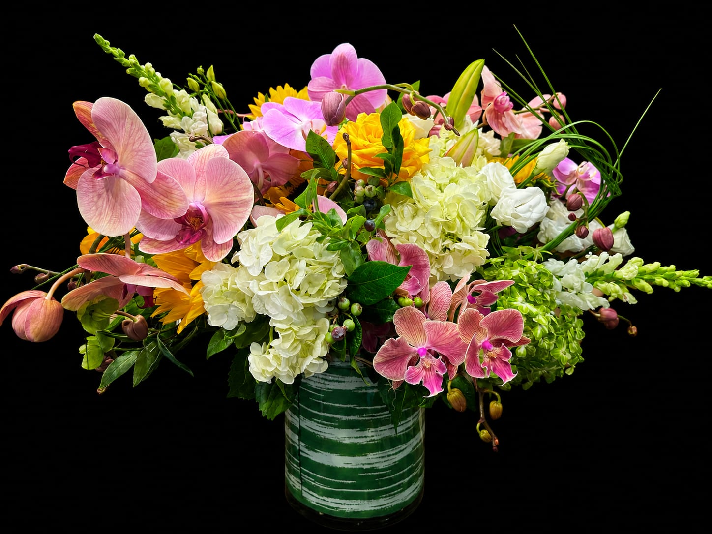 Summer Garden Luxe Floral Arrangement - Features:  Premium fresh-cut flowers Handcrafted by professional floral designers Modern green ceramic keepsake vase included Approximately 28–32 inches wide and 24–28 inches tall (may vary slightly) Designed with the freshest seasonal blooms for long-lasting beauty