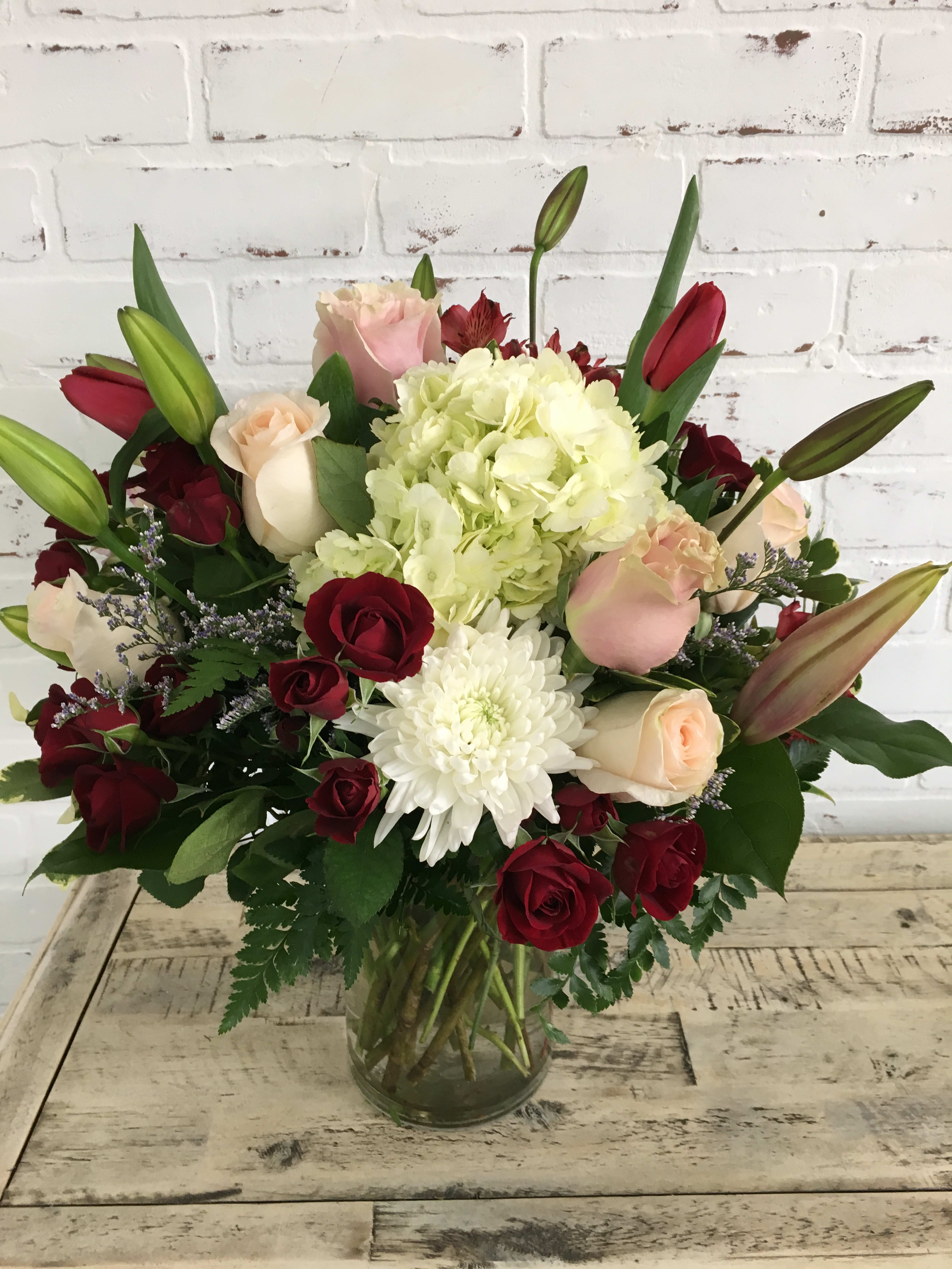 Bouquet of red and blush roses with white hydrangea in a glass vase