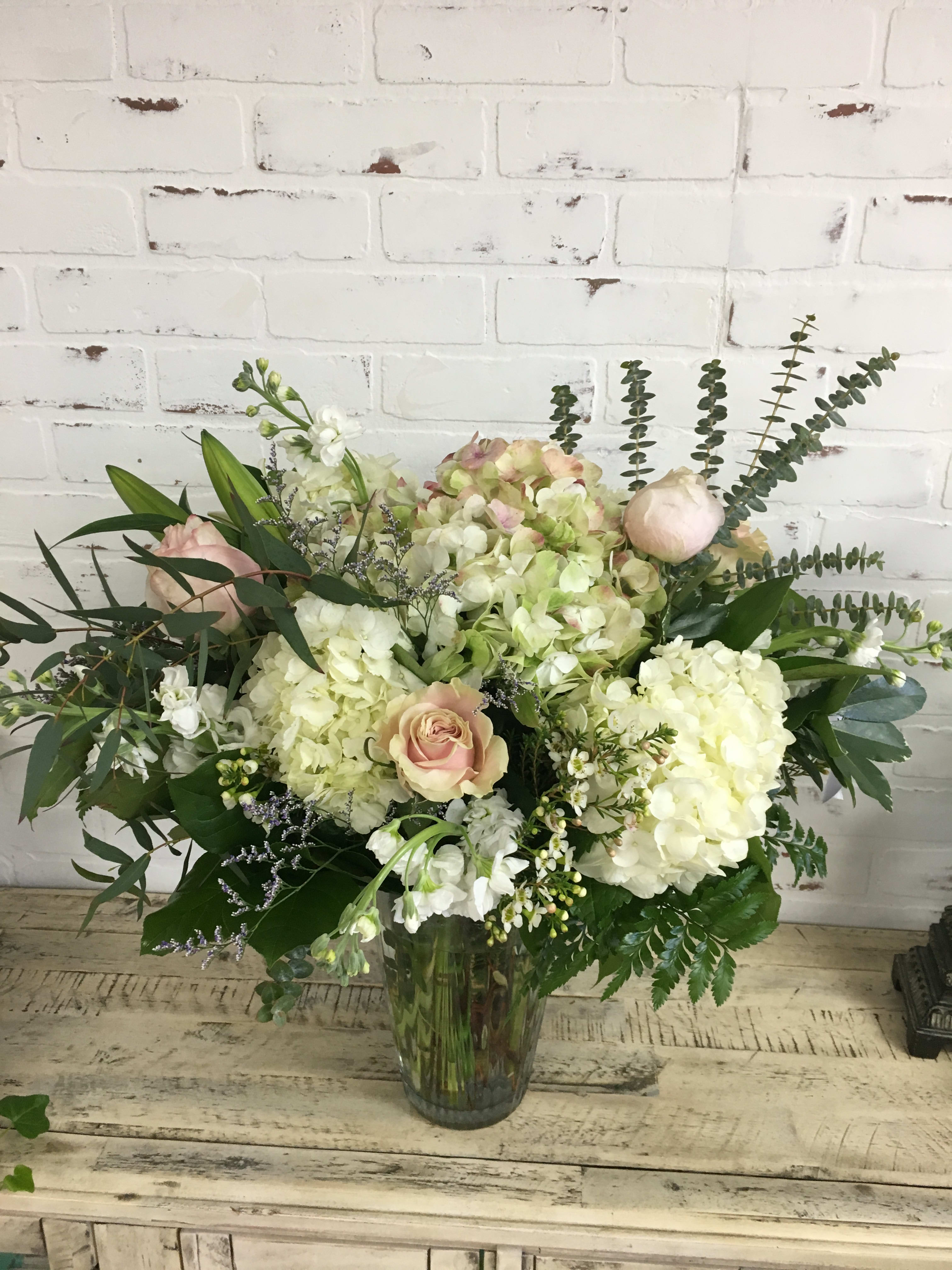 Large bouquet of pale hydrangeas and blush roses in a glass vase