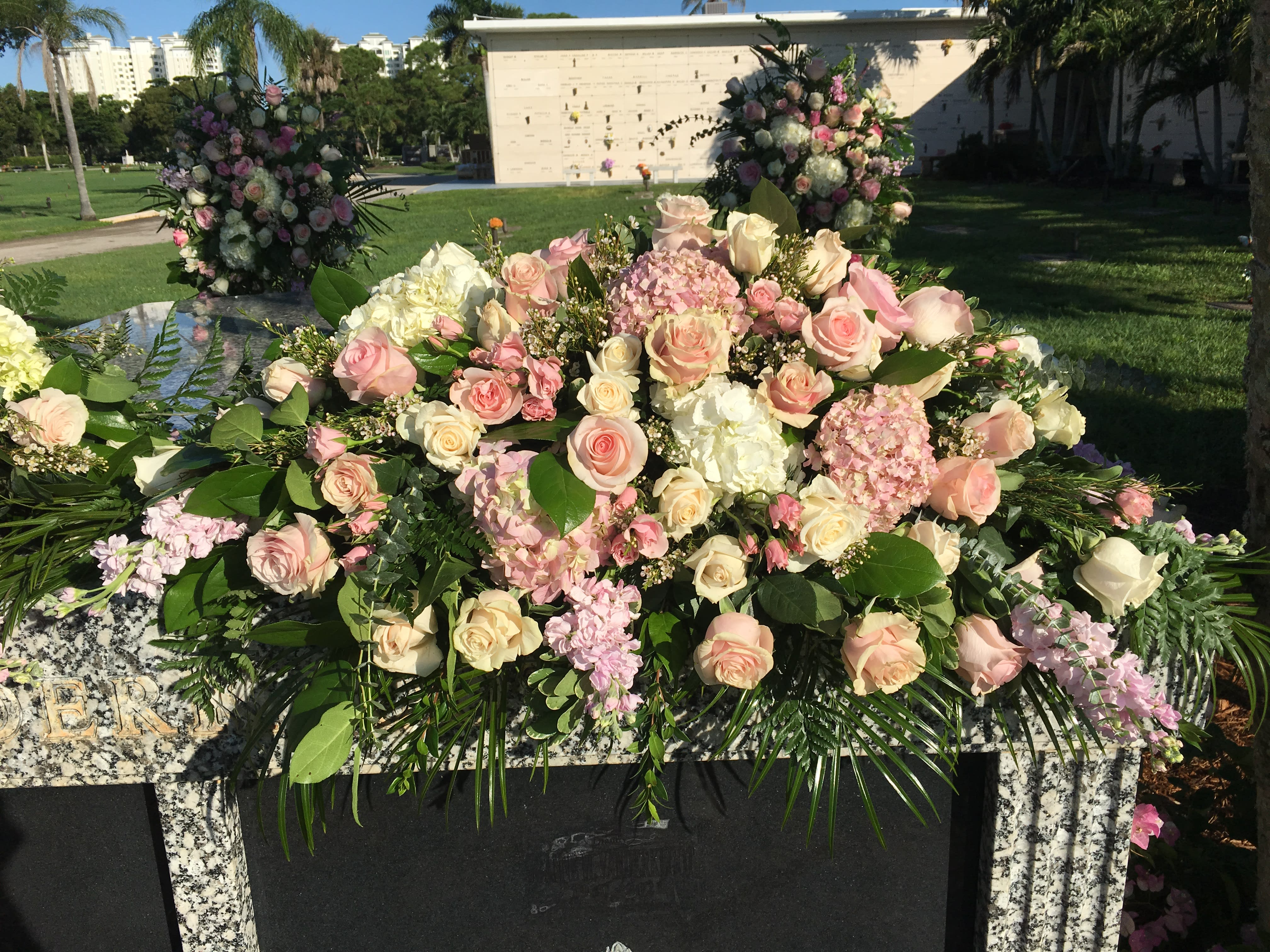 Large pink and white floral arrangement on a stone memorial