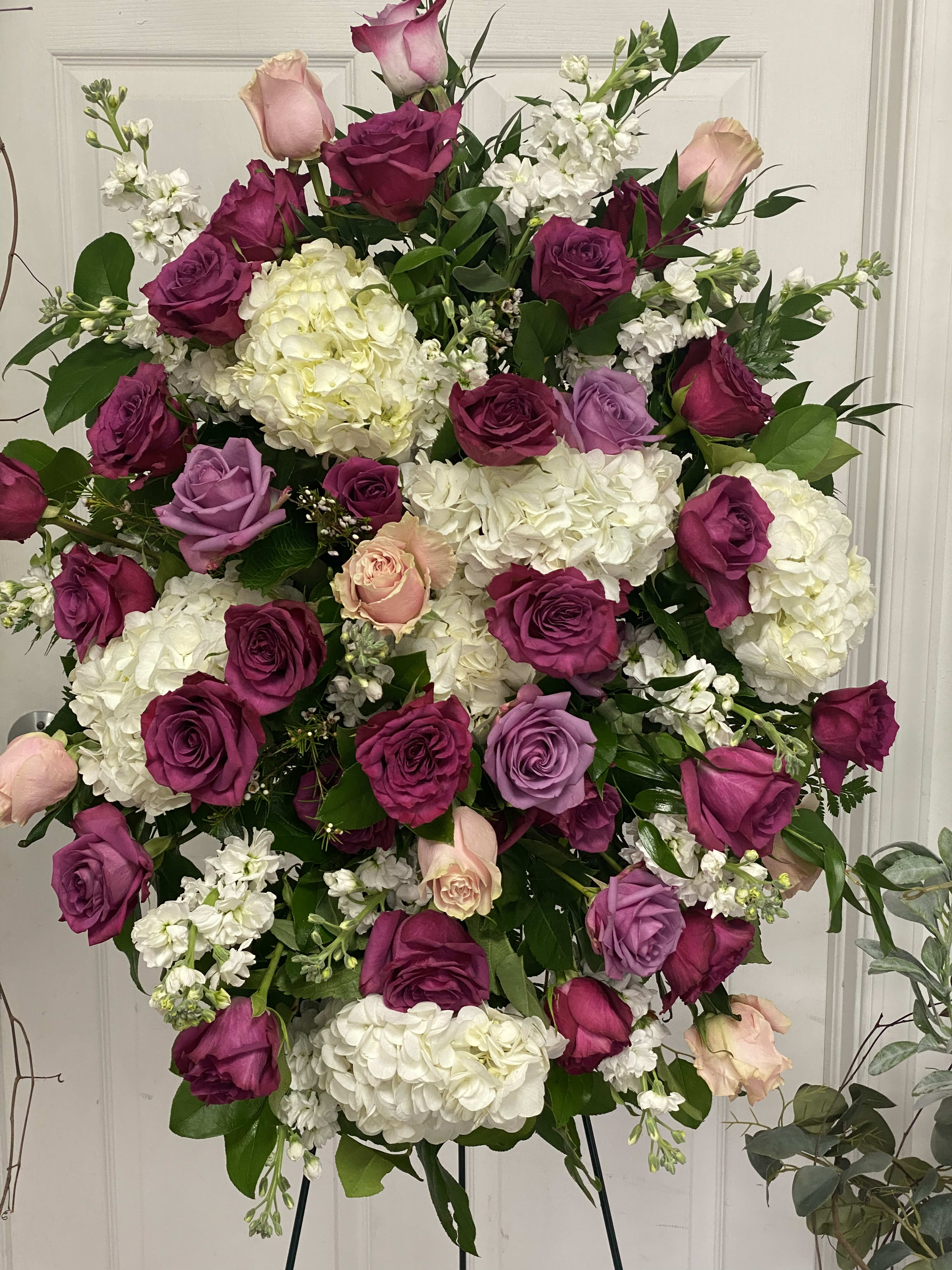 Large standing spray of pink, purple, and white roses with white hydrangeas