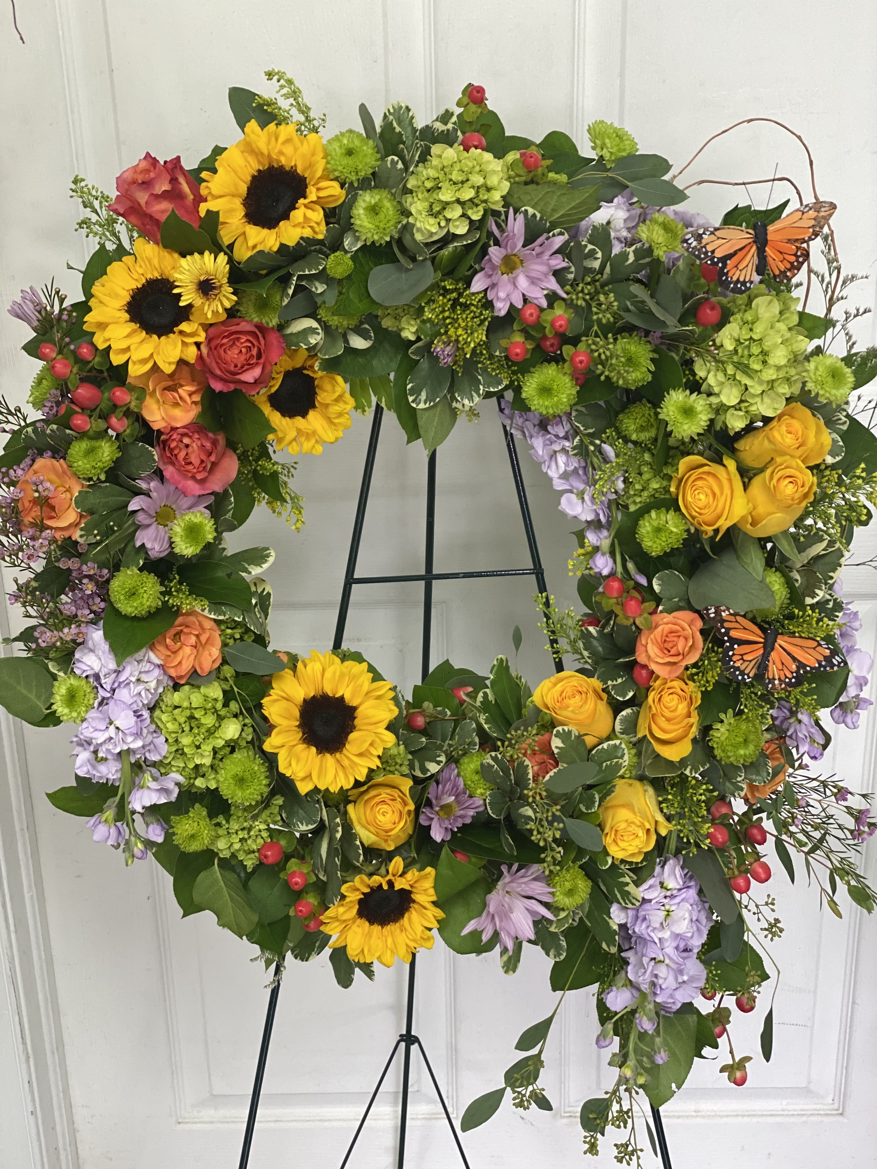 Heart-shaped floral wreath with sunflowers, roses, and butterflies