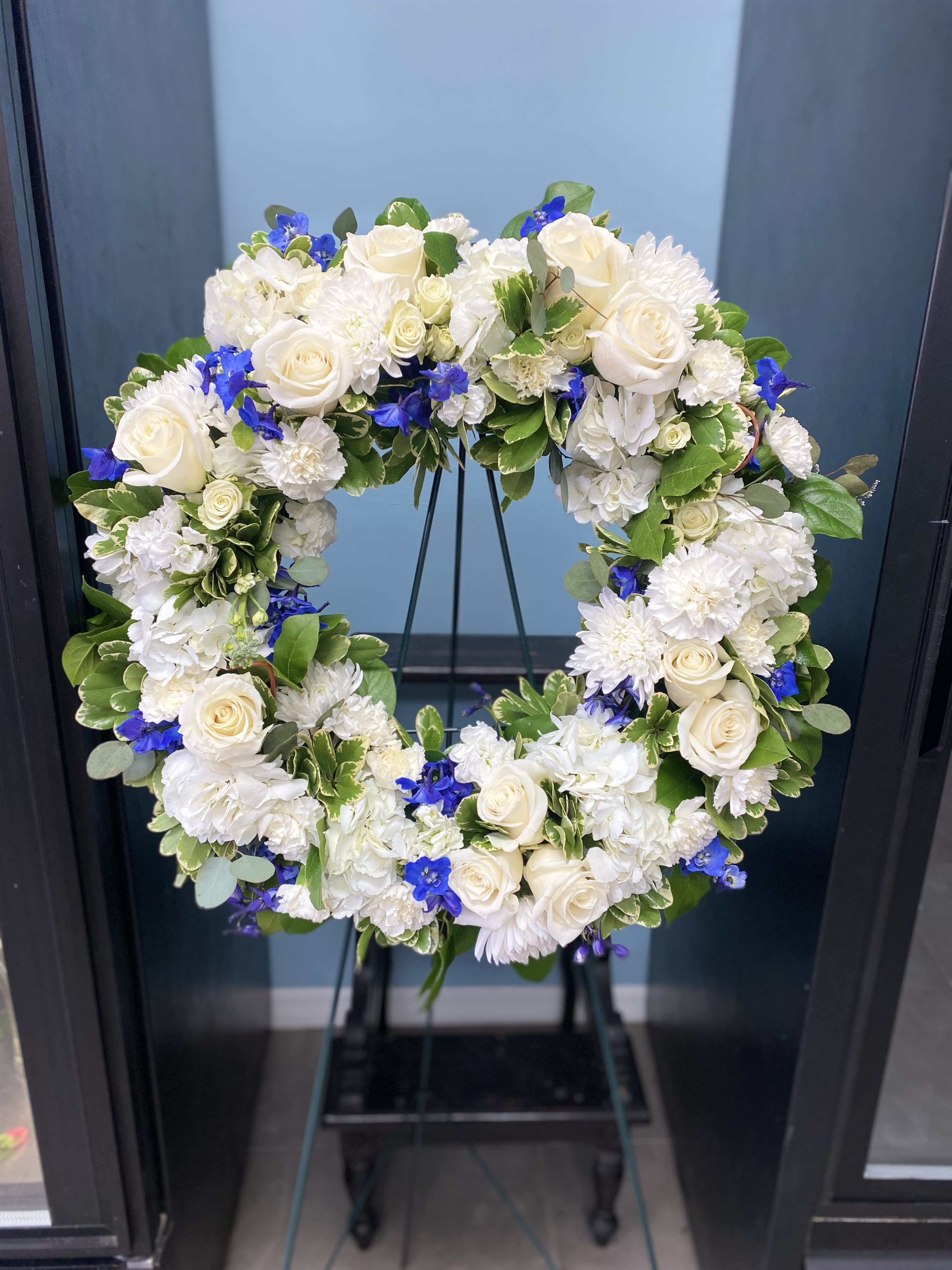 White and blue floral wreath on a stand