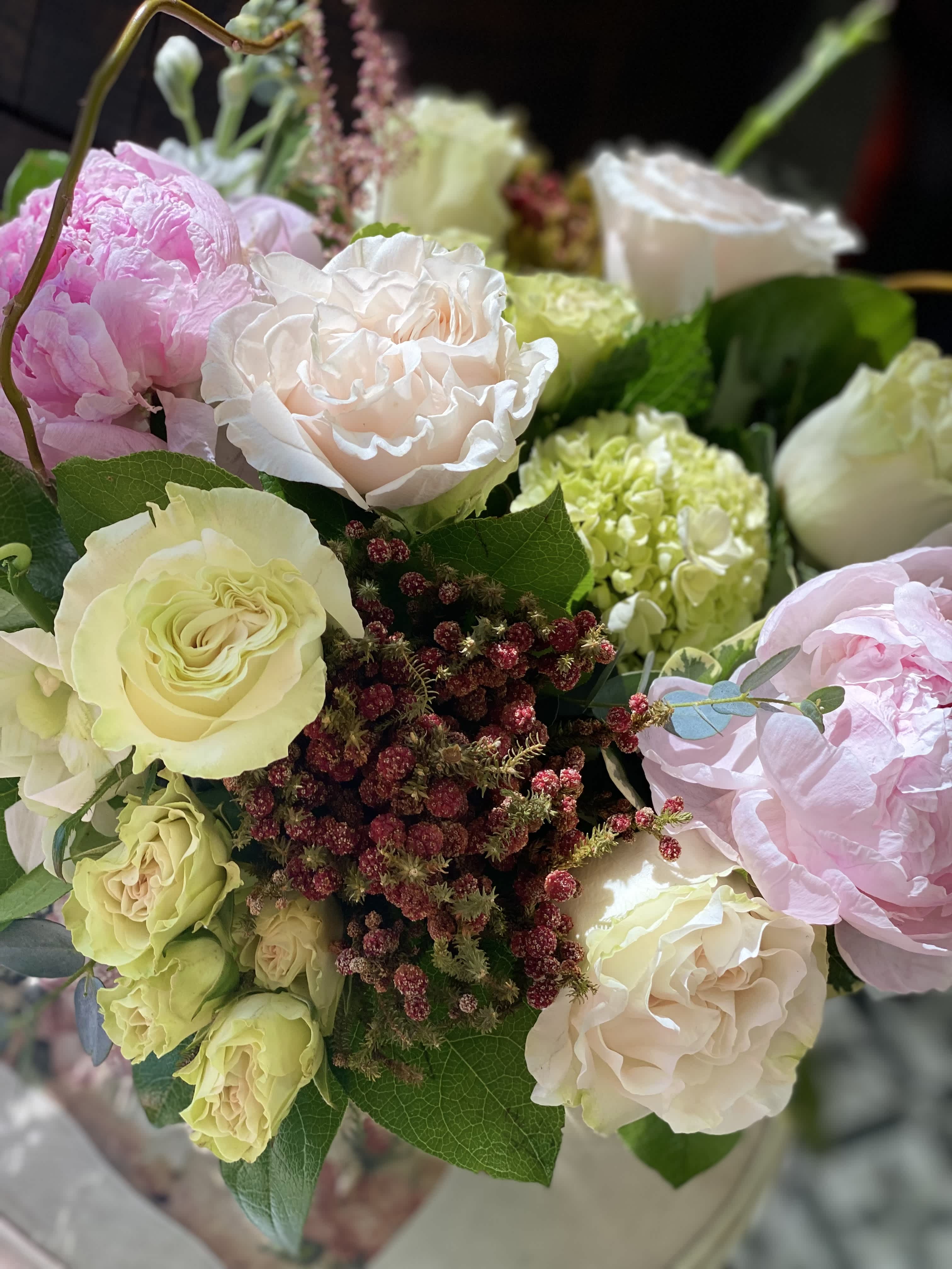 Arrangement of blush roses, green hydrangea, and pink peonies in a vase