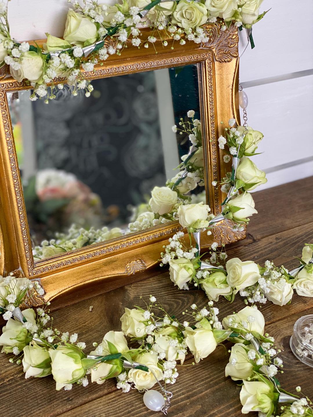 White rose garlands draped around an ornate gold mirror