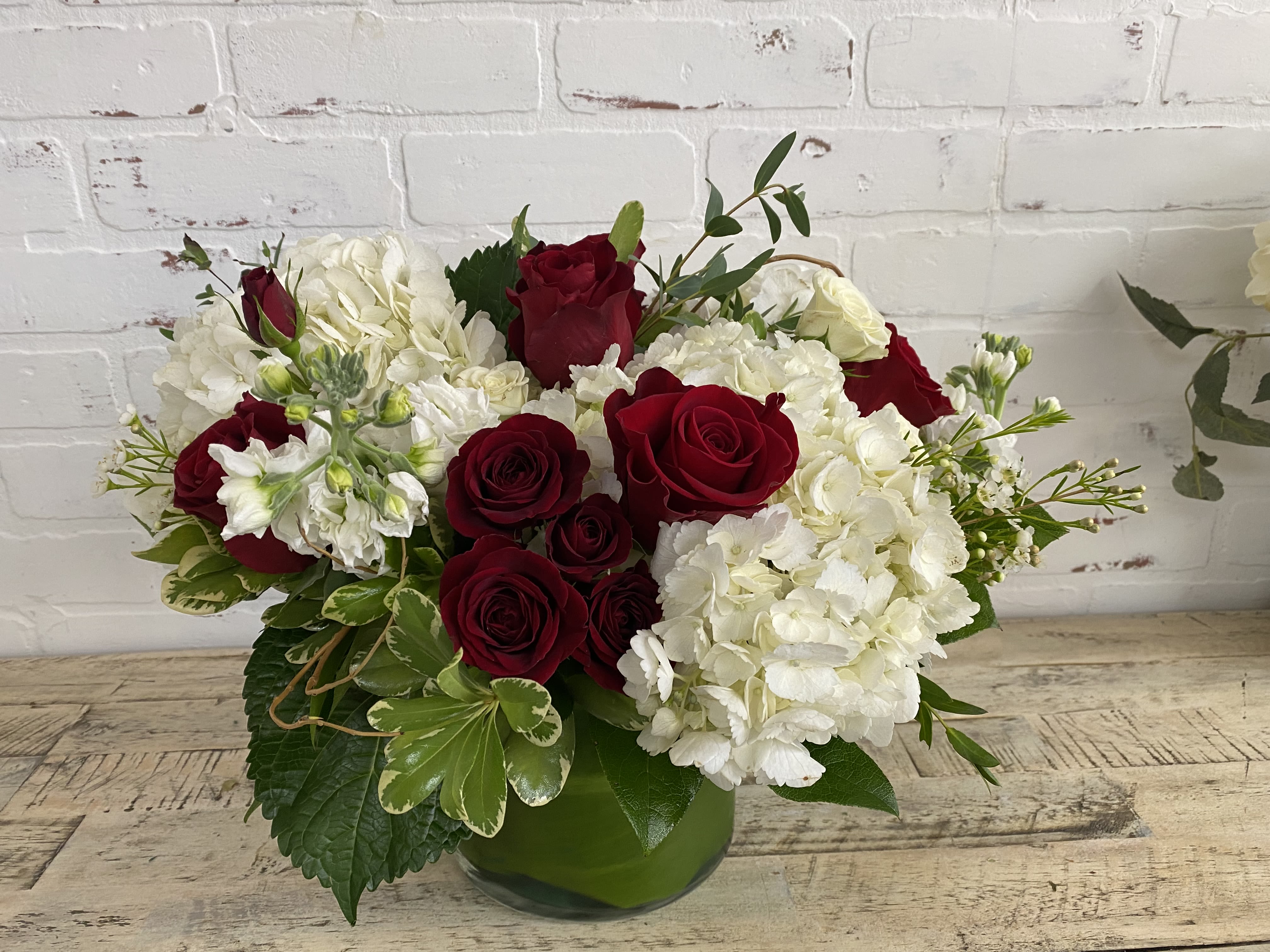 Red roses and white hydrangeas in a green glass vase