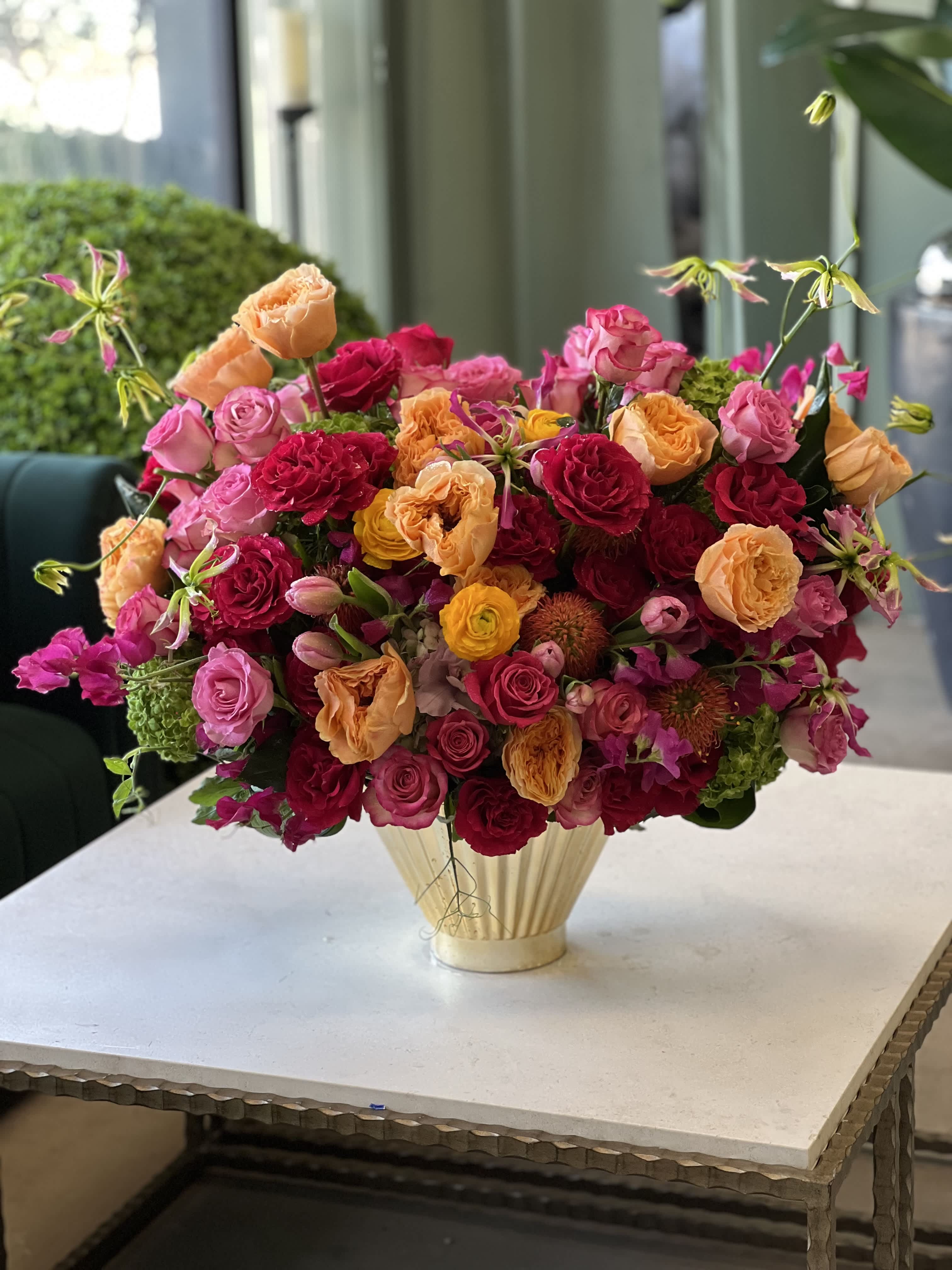 Mixed bouquet of pink, red, and peach roses in a gold vase