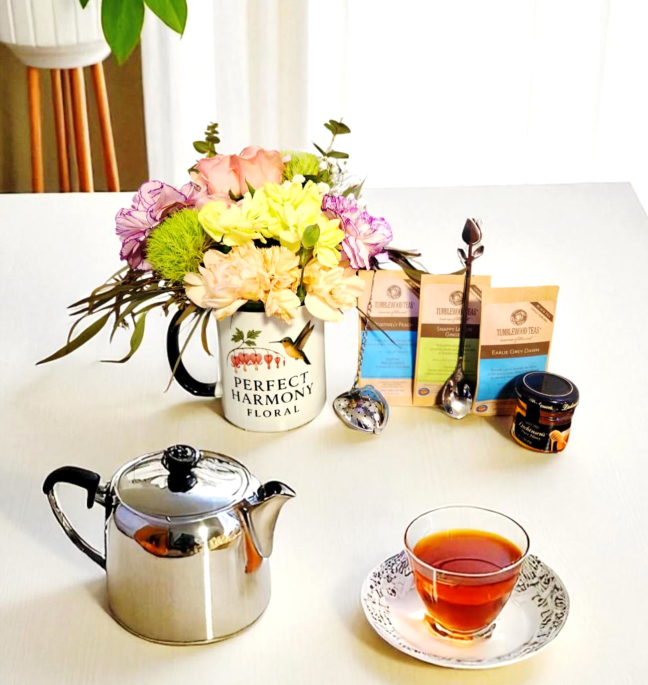 Flower arrangement in a mug with tea bags, teapot, and a cup of tea