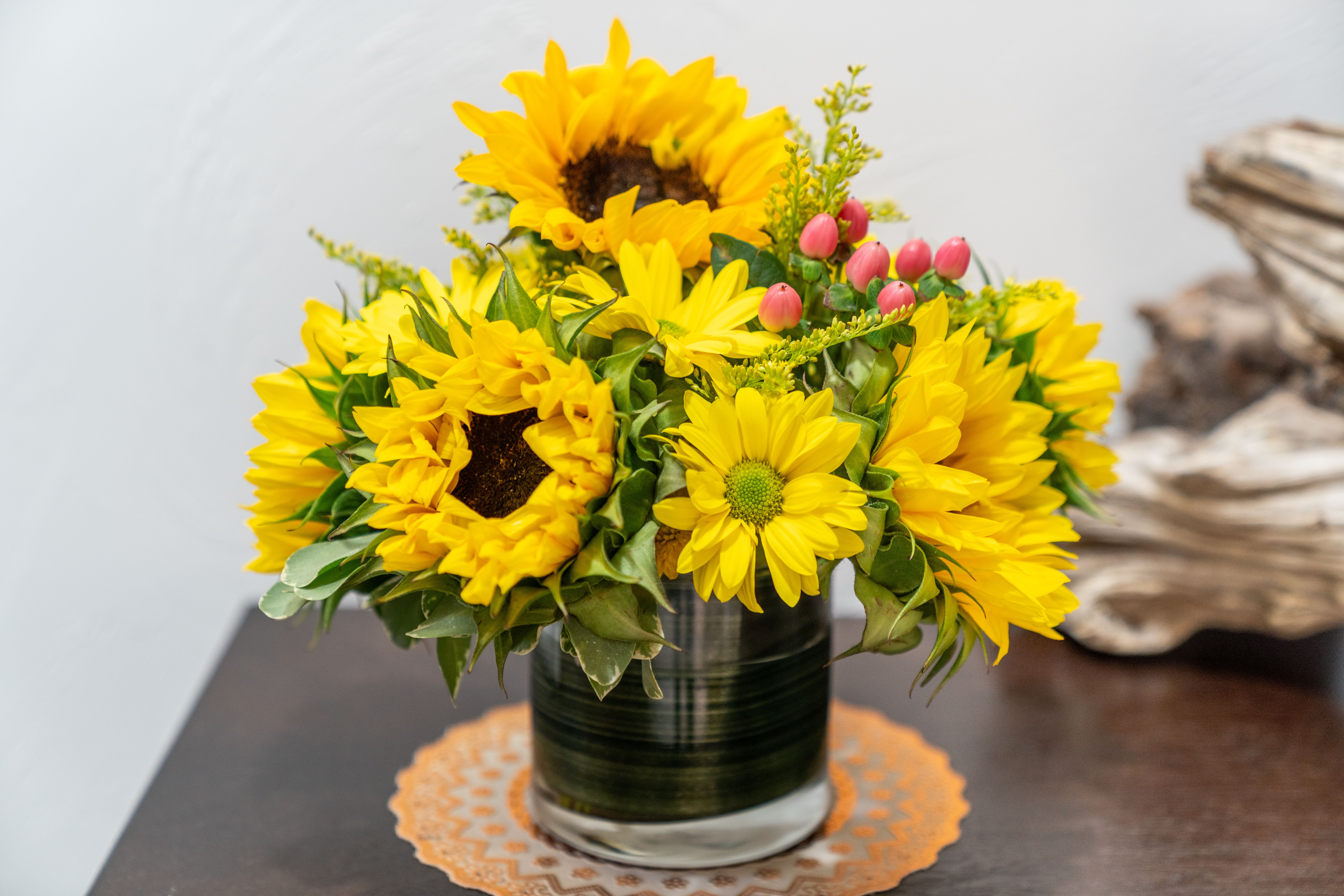 Sunflower Delight - This delightful bouquet features brilliant sunflowers complemented by fresh greenery and cheerful pink/red hypericum berries. In short, a pocket full of sunflowers.    