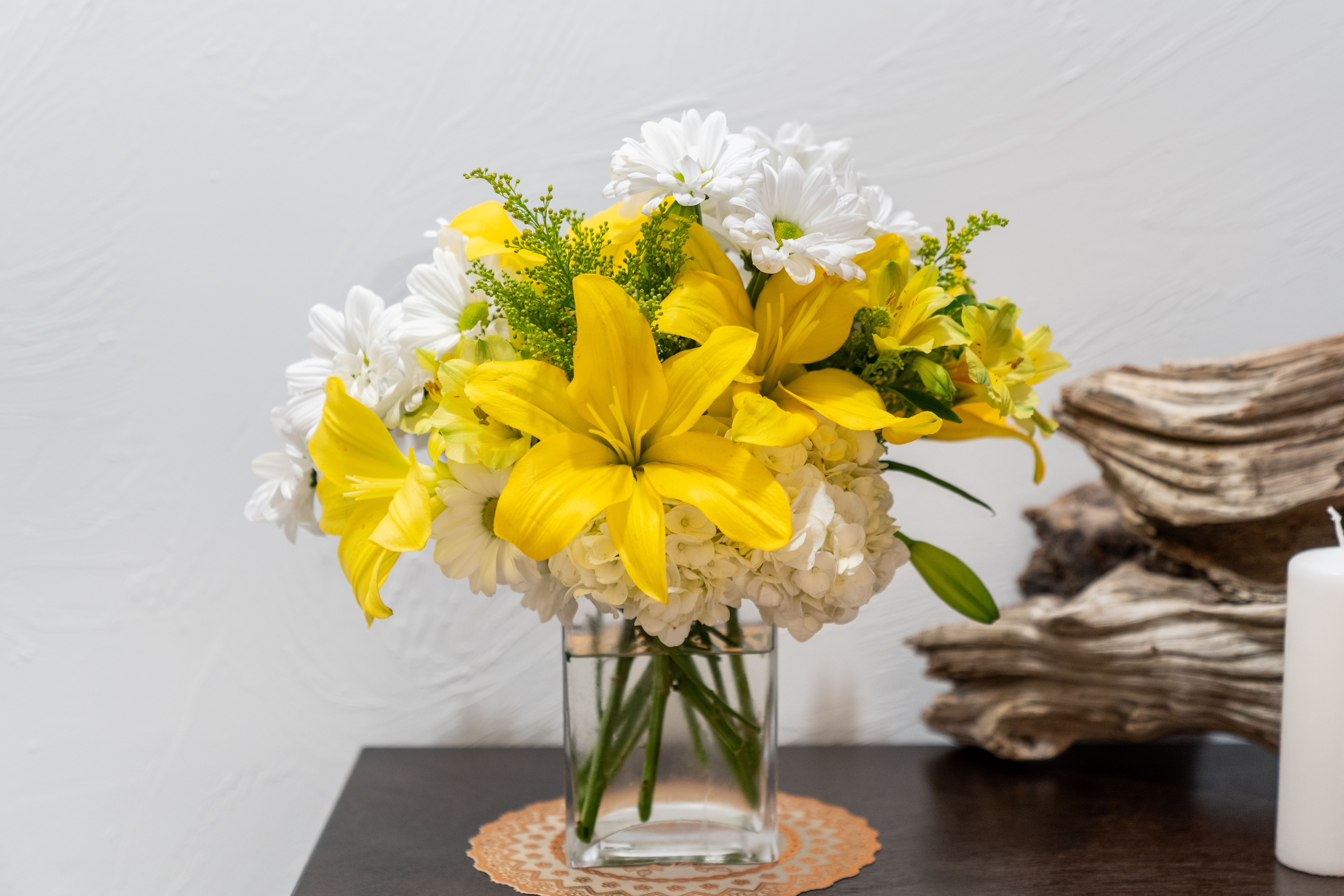Yellow lilies and white daisies in a clear glass vase