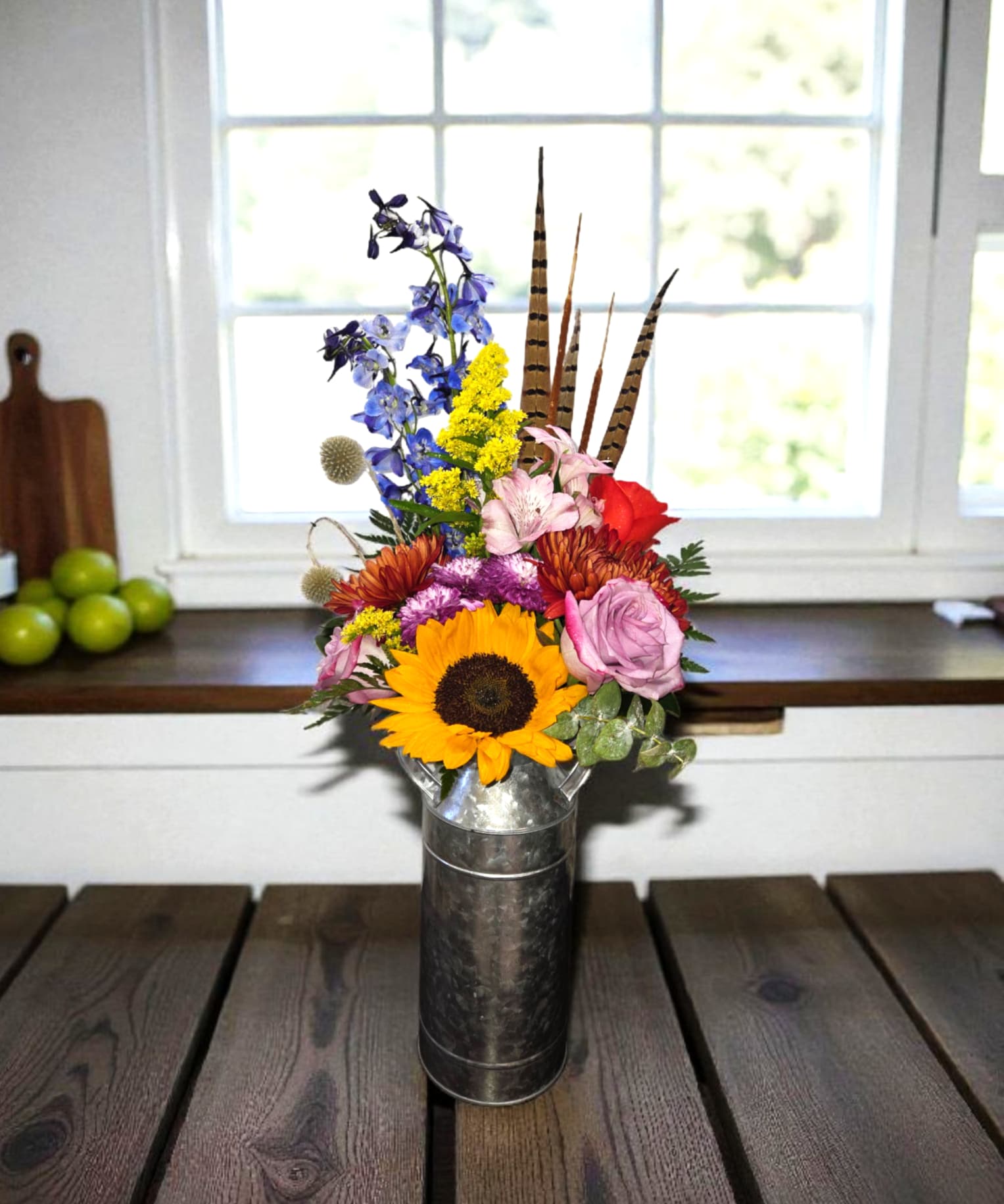 Mixed bouquet with a sunflower, roses, and blue flowers in a metal vase