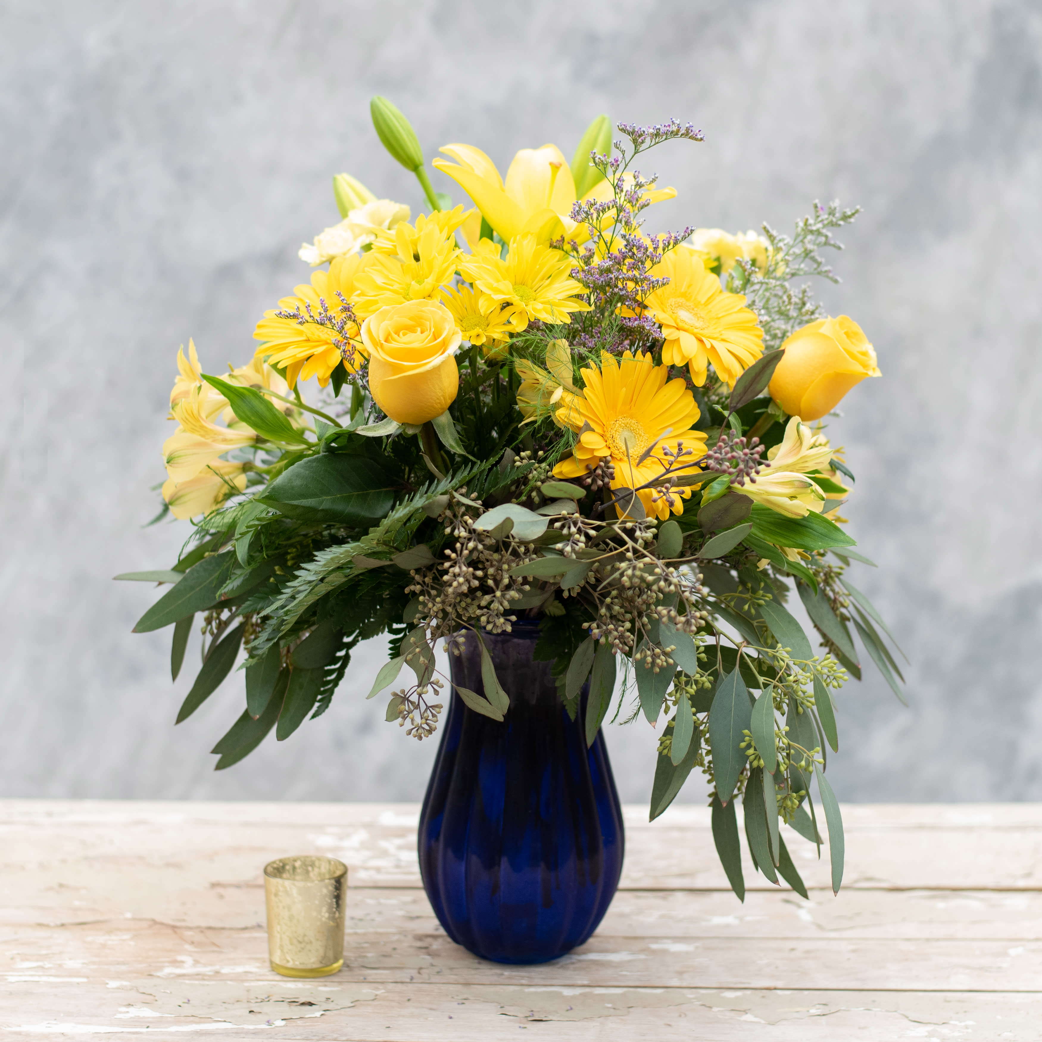 Sunny - The perfect way to brighten any room, add this 8" blue swirl vase overflowing with premium greens and nothing but yellow flowers, including roses, gerbera daisies, alstroemeria, lilies, daisies and more! Turn the darkest day, Sunny!