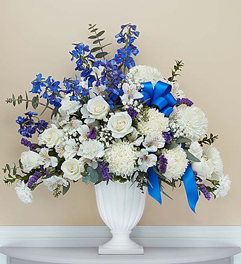 White and blue floral arrangement in a white urn vase