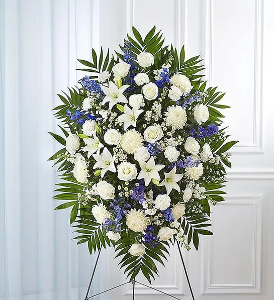 Standing funeral spray of white and blue flowers on an easel