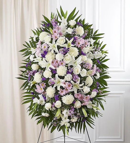 Standing funeral spray of white and lavender flowers on an easel