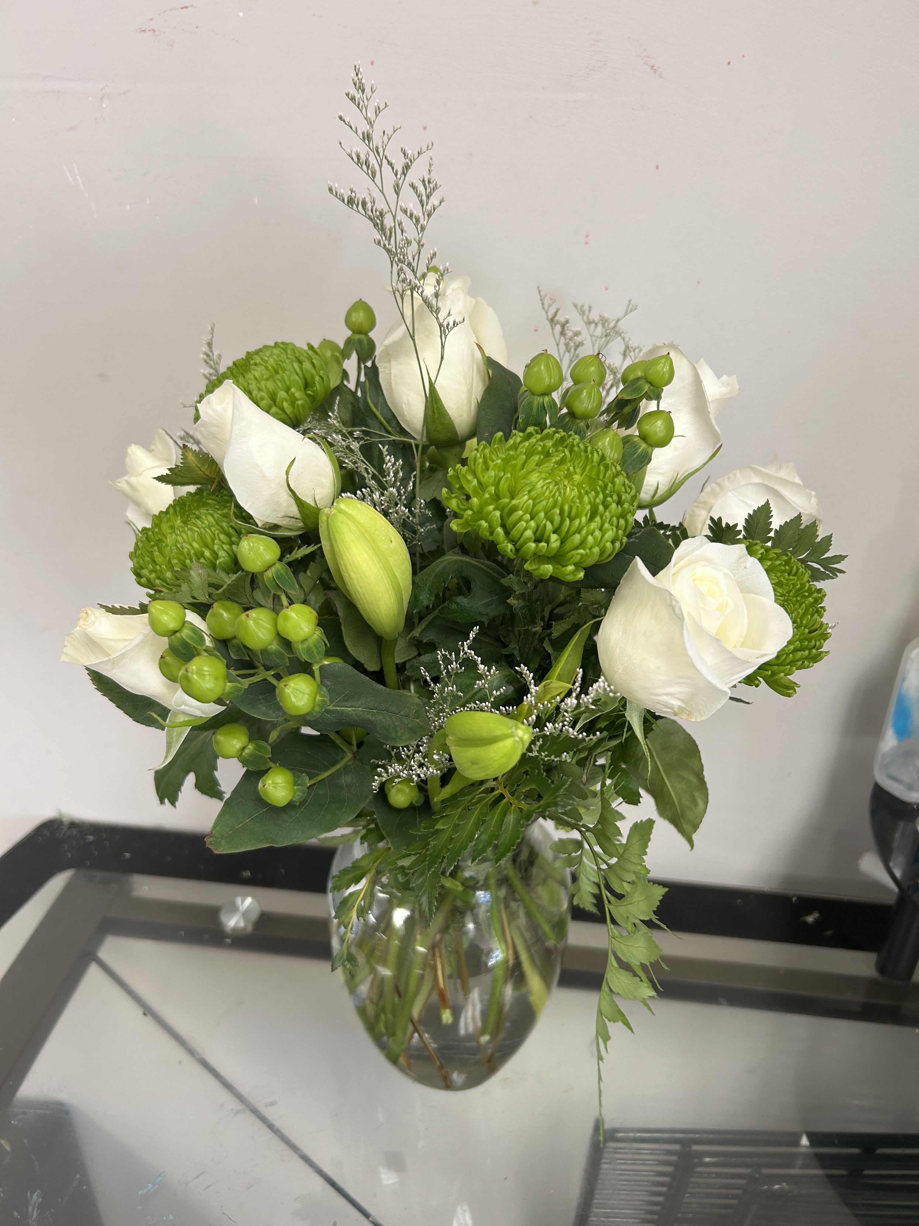 White roses and green chrysanthemums in a glass vase