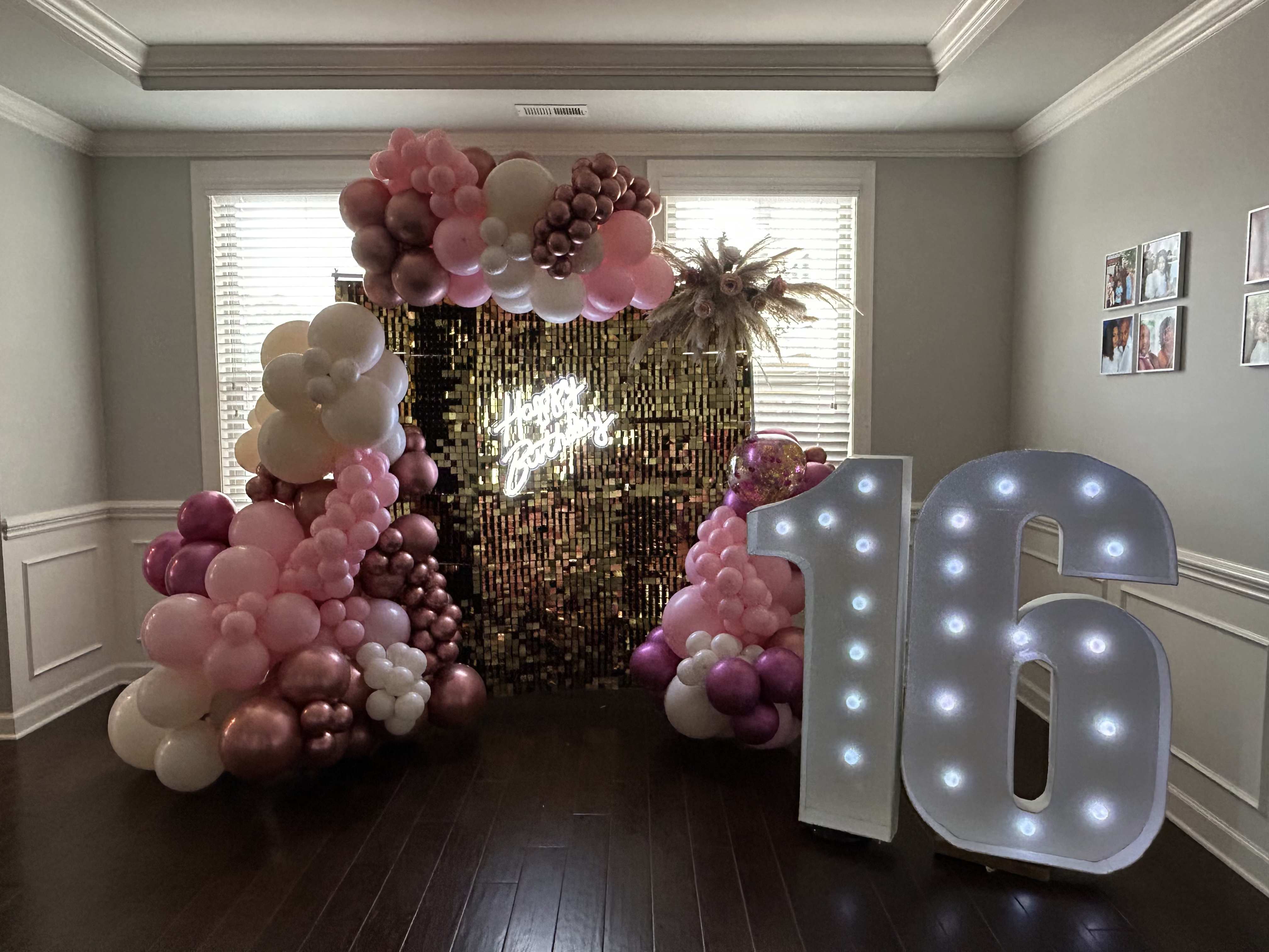 Pink and white balloon arch with a lit "16" sign and gold backdrop