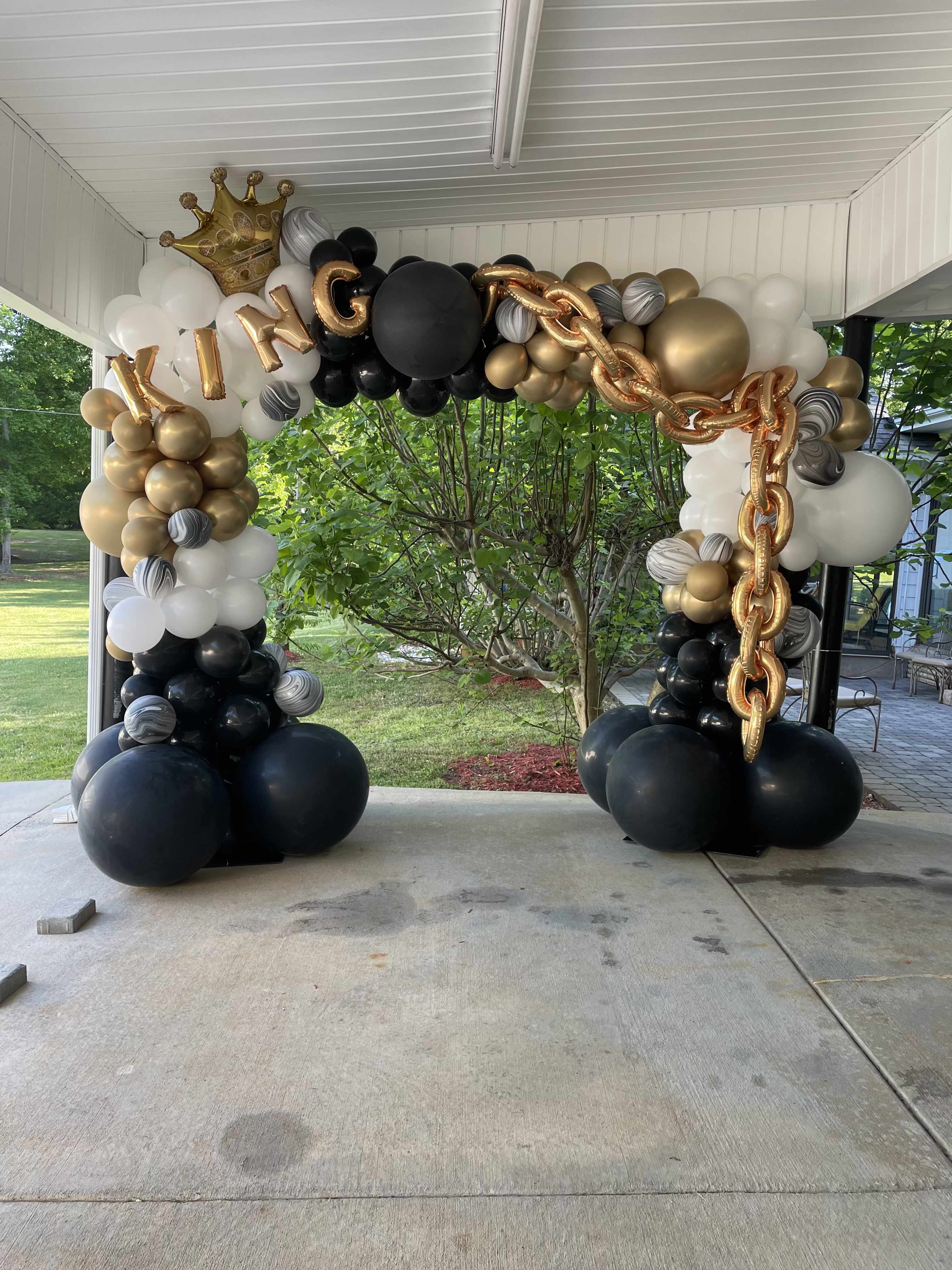 Black, white, and gold balloon arch with a crown and "KING" letters
