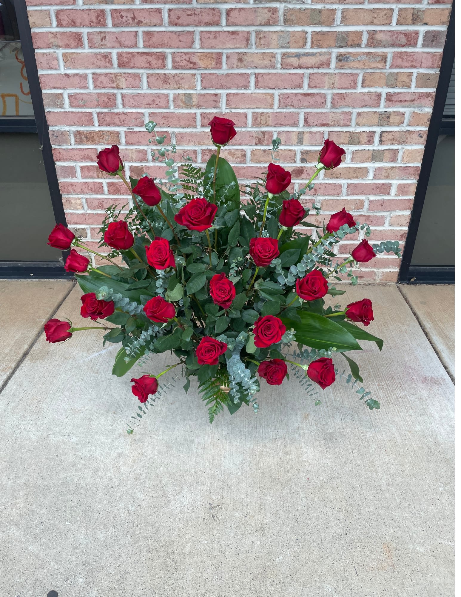 Arrangement of red roses with greenery on the ground