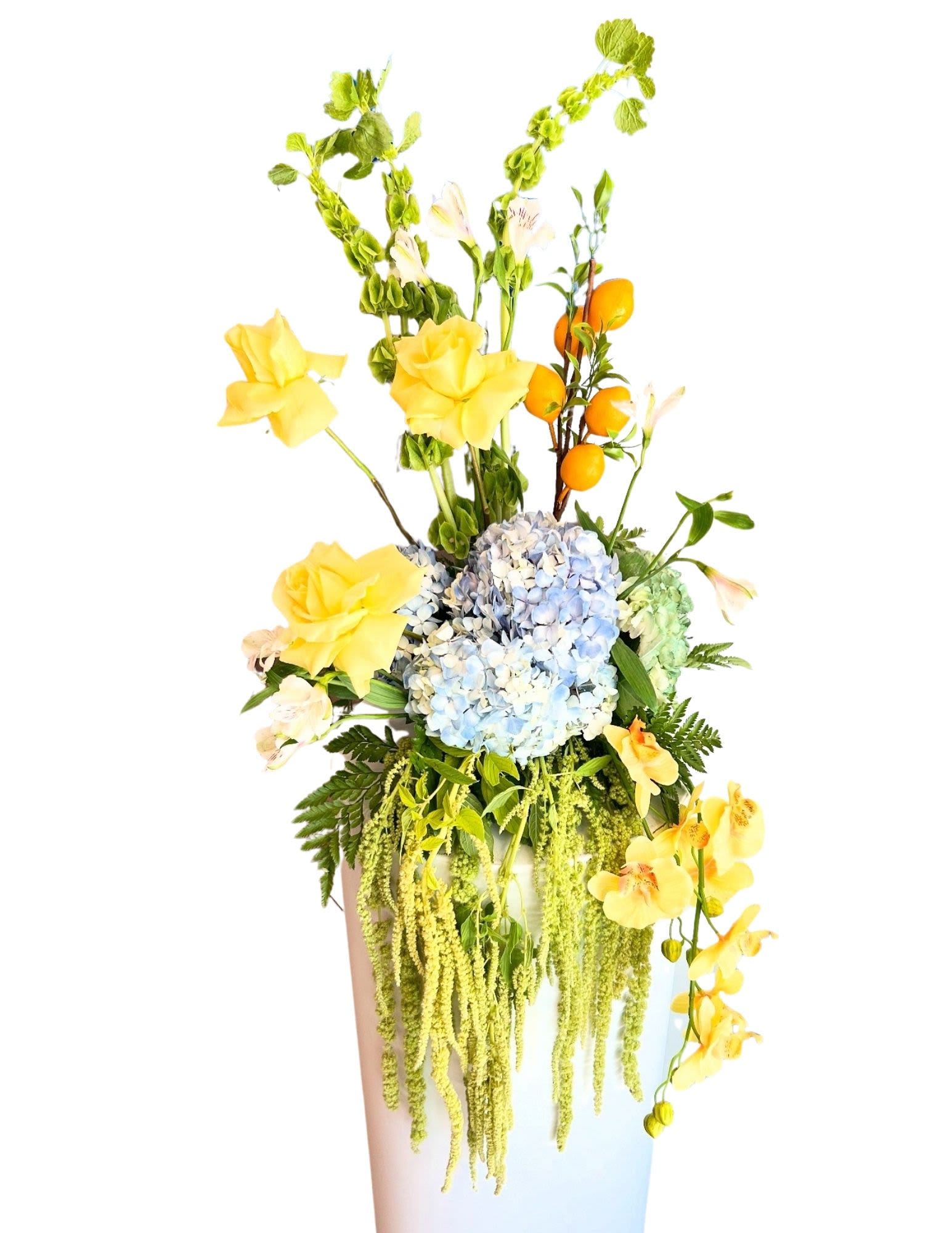 Tall floral arrangement with blue hydrangea and yellow orchids in a white vase