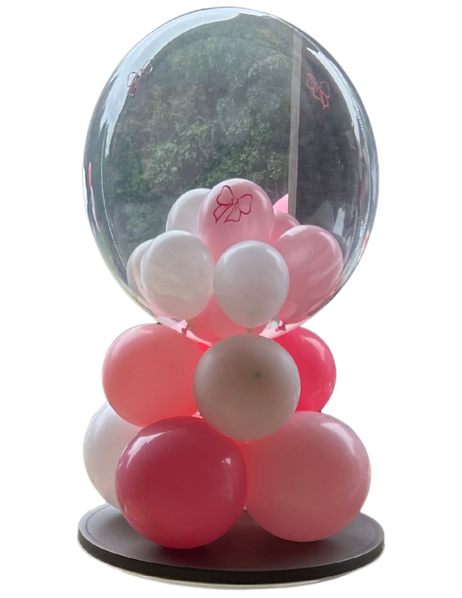 Pink and white balloons inside a clear balloon dome on a black base