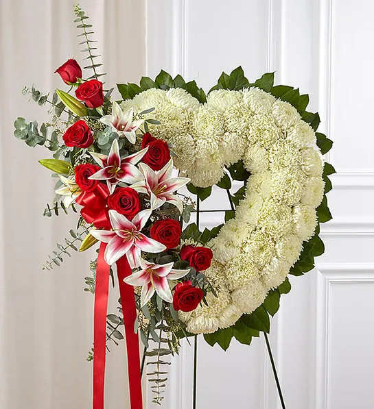 Always Remember Floral Heart Tribute Red Rose &amp; Lily - The passing of someone we love deeply requires a special tribute. Our open heart standing arrangement of fresh white blooms, accented by red roses and Stargazer lilies cascading down one side and adorned with a red satin ribbon, will help you express the devotion and sympathy in your heart.