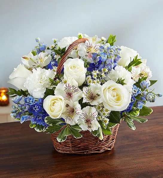 White roses and blue flowers arranged in a wicker basket