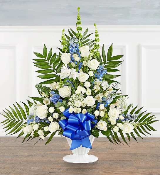 Tranquility Floor Basket  Blue &amp; White -  Offer comfort and tranquility with a truly special display. Our floor basket arrangement is a unique addition to the services, standing over three feet high with lush greenery that cascades out for an elegant presentation. This stylish design is gathered with a flourish of blue &amp; white blooms, creating a beautiful tribute to celebrate their life..Floor basket arrangement with white roses, snapdragons, Peruvian lilies (alstroemeria), button poms and Queen Anne’s lace, blue delphinium, green Bells of Ireland; accented with spiral eucalyptus, 