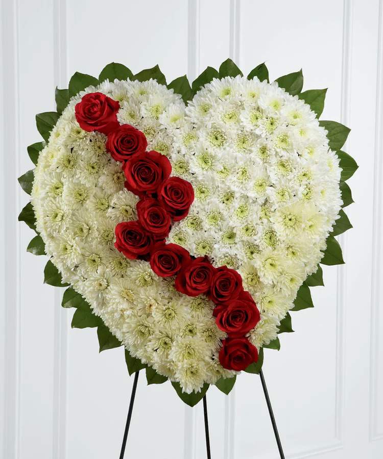 The Broken Heart Standing Spray  - Honor a loved one with a special tribute. Our heart-shaped .The Broken Heart is a beautiful way to express the impact that the departed had on your life. Pearly white chrysanthemums form the shape of a heart, accented with greens lined around the outside and "broken" in the middle with a line of rich red roses to create an exquisite way to honor the life of the deceased at their memorial service.