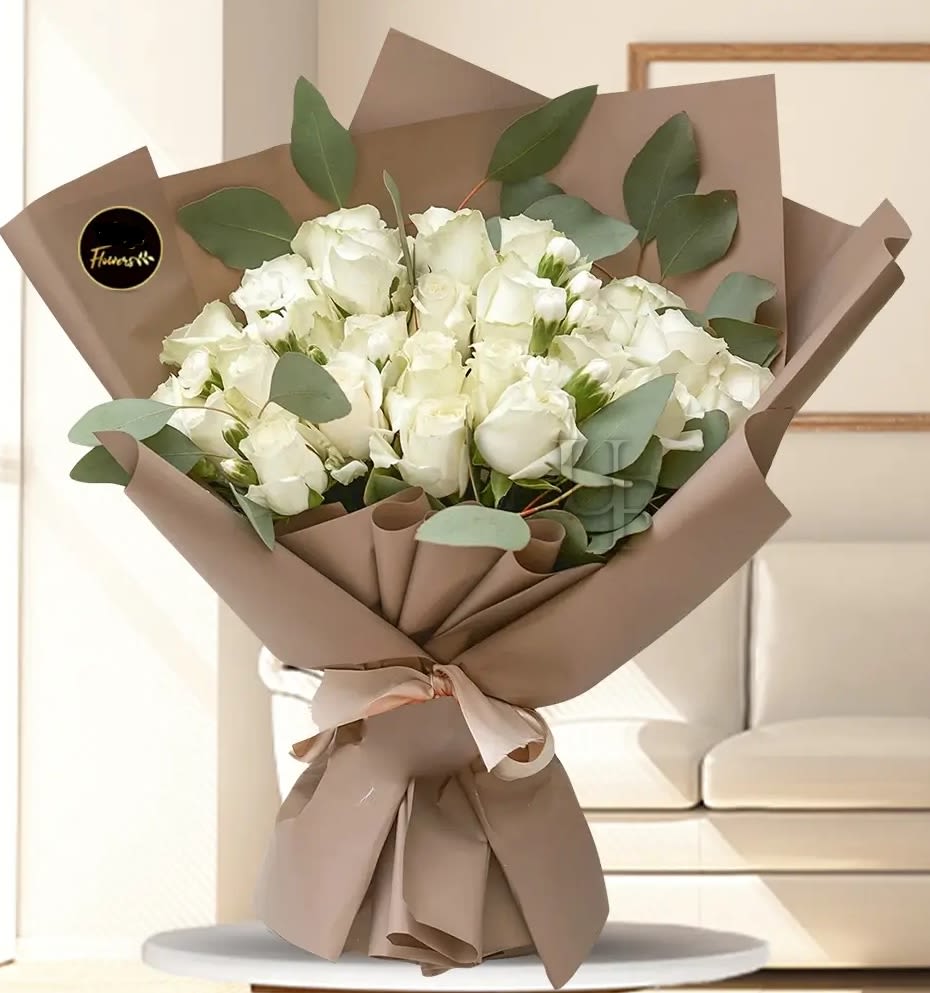 Bouquet of white roses wrapped in brown paper with eucalyptus
