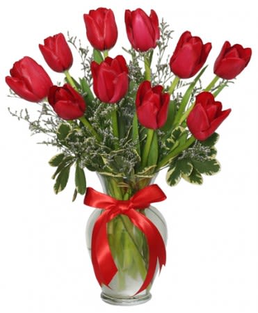 Red tulips arranged in a glass vase with a red ribbon