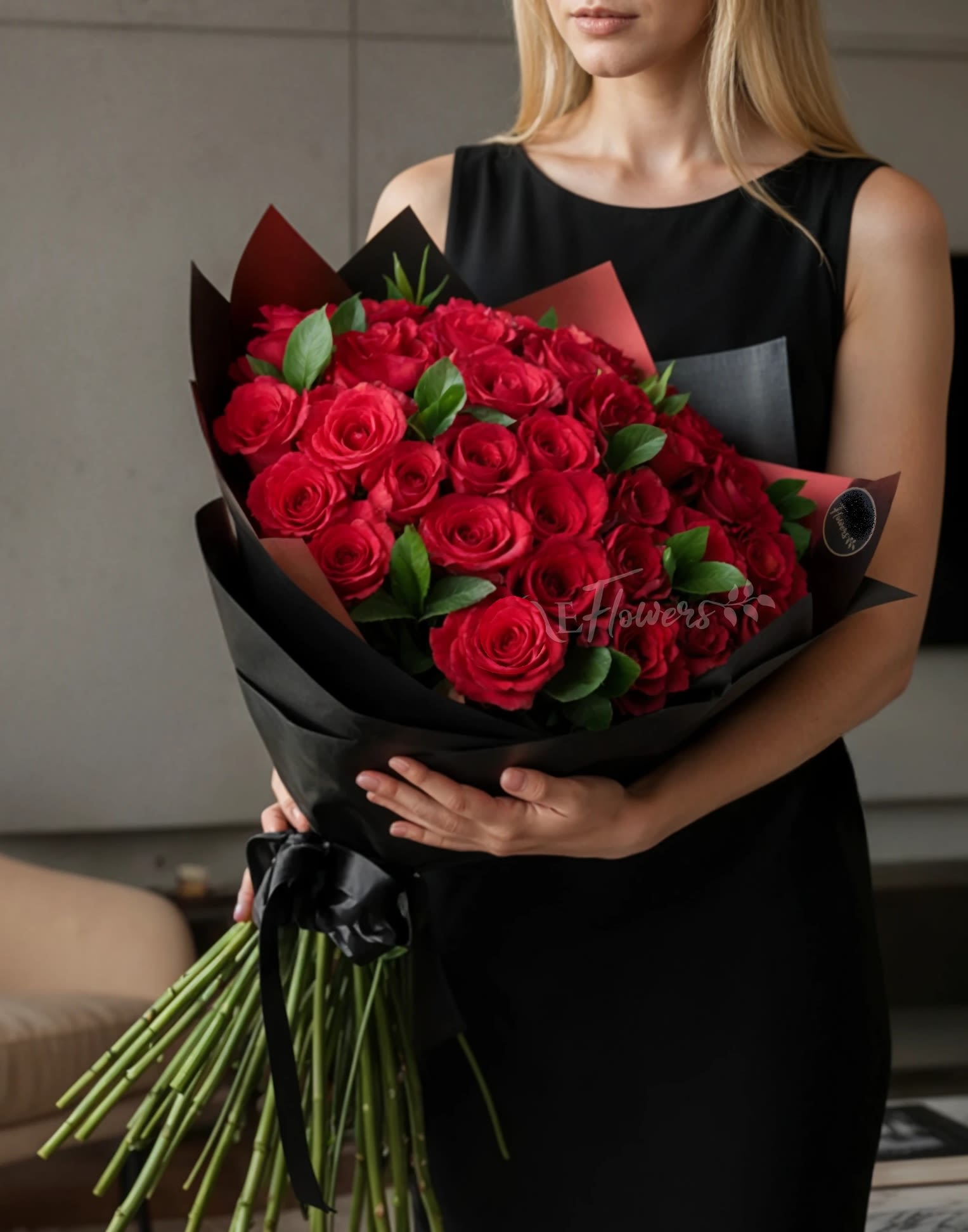 Woman holding a large bouquet of red roses wrapped in black paper