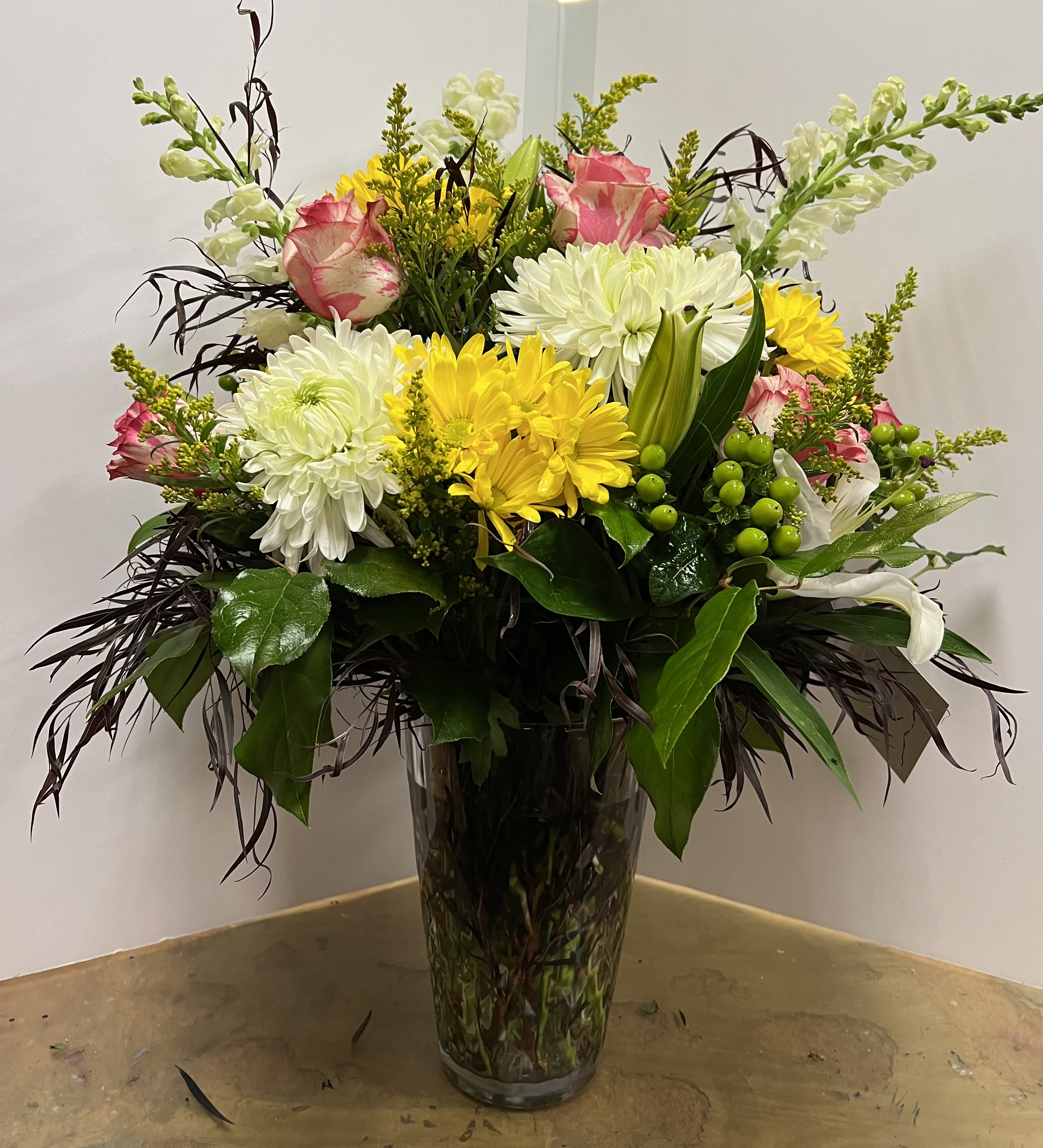 Mixed bouquet of white and yellow flowers in a tall glass vase