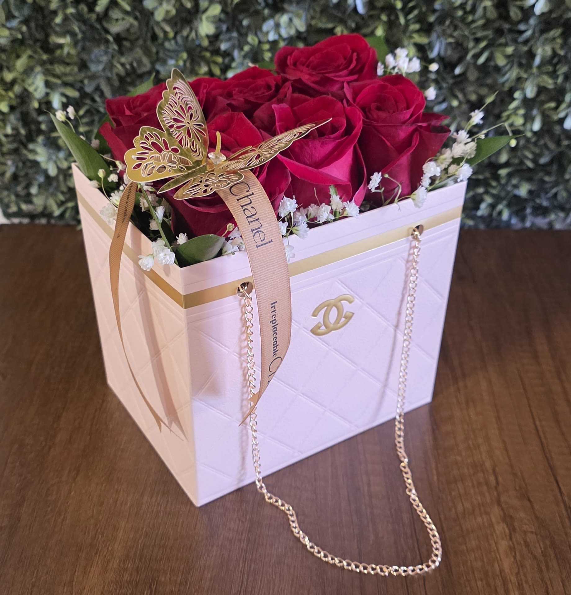 Red roses in a white gift box with a ribbon and butterfly decoration