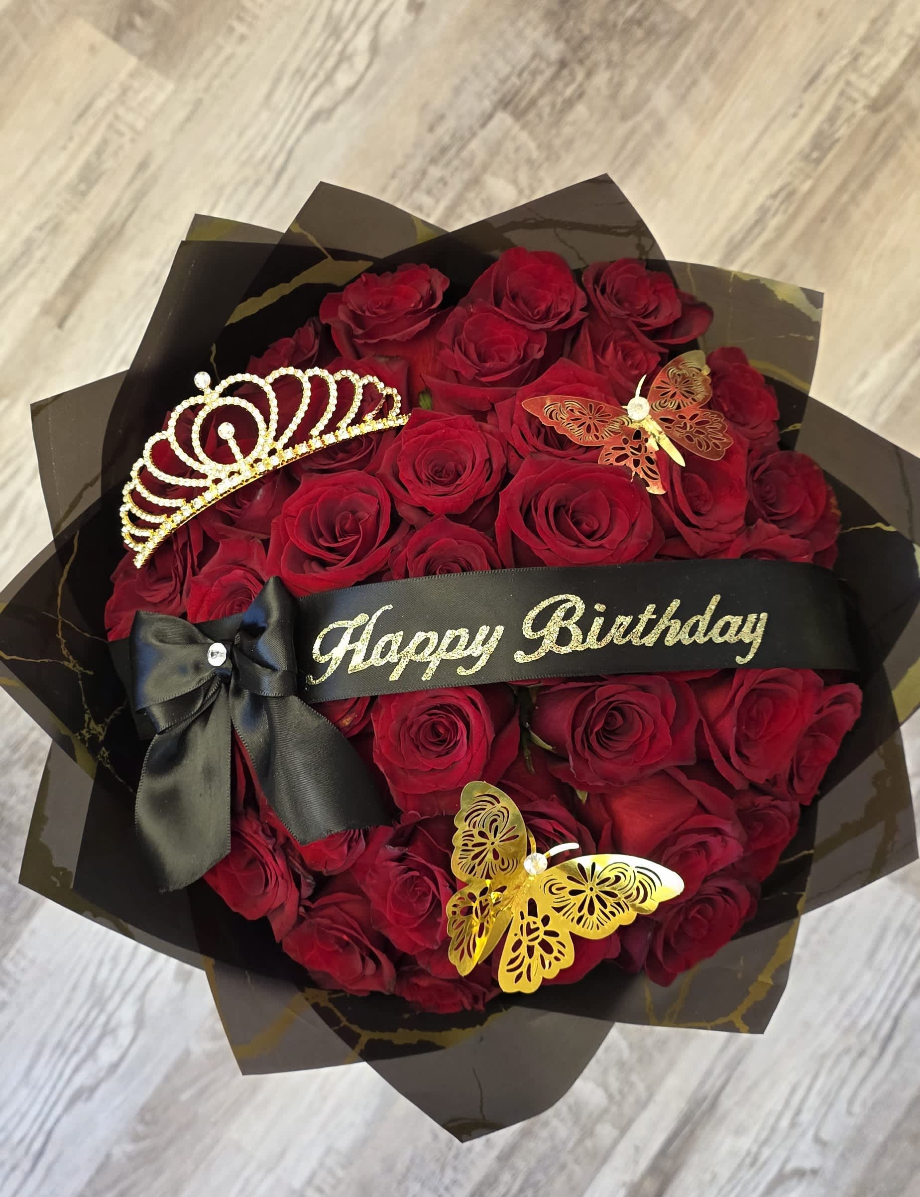 Red rose bouquet with a black birthday ribbon, bow, and decorative tiara
