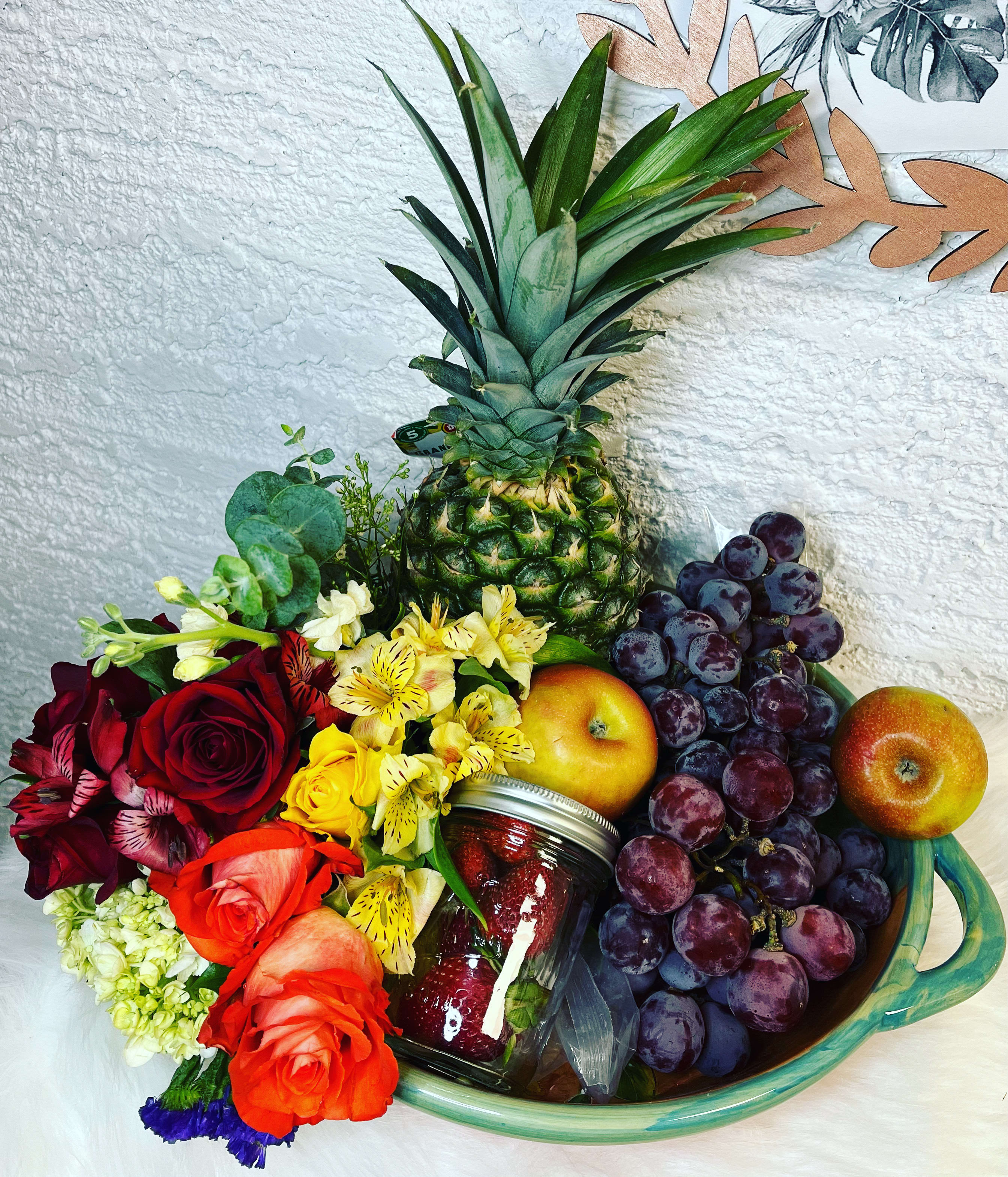 Fruit basket with roses, grapes, pineapple, apples, and a jar of strawberries