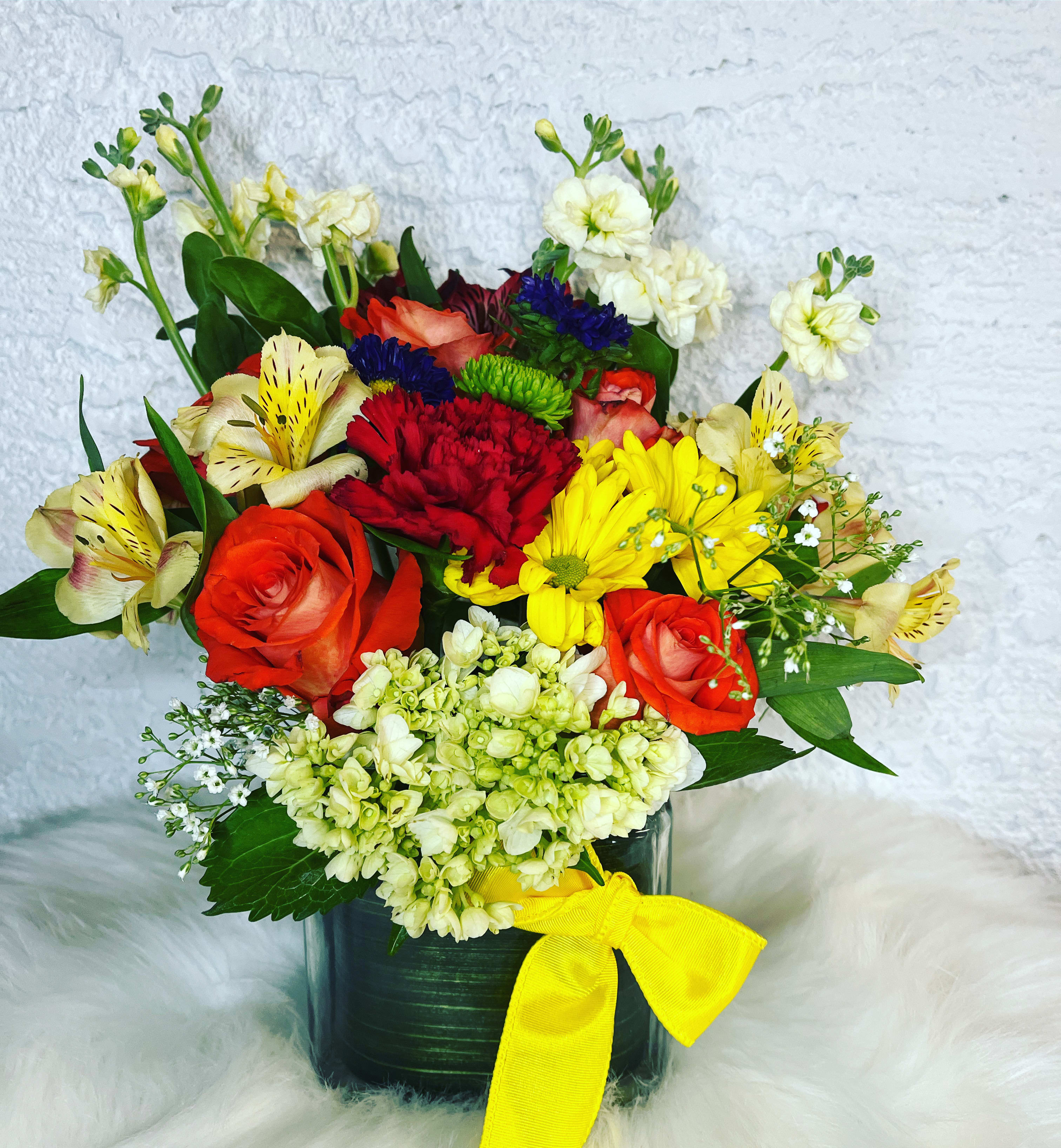 Mixed bouquet in a dark vase with a yellow ribbon