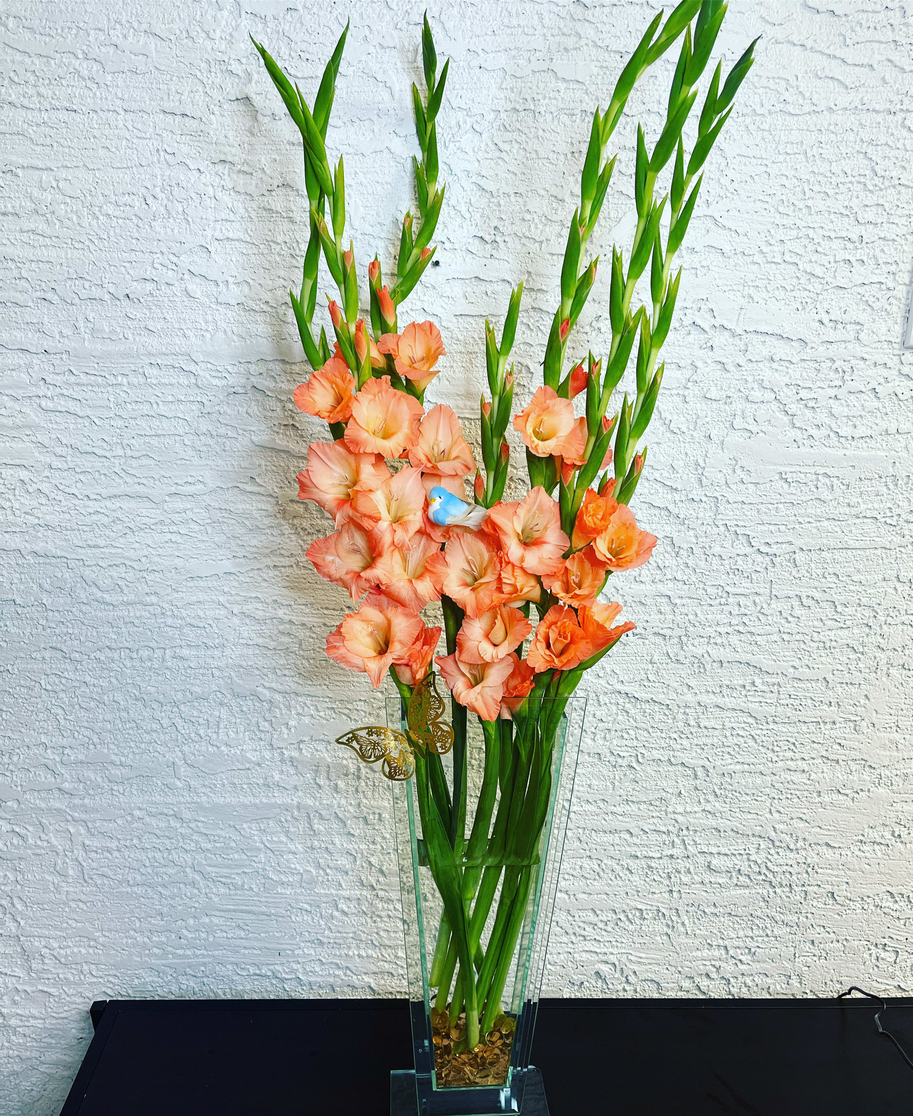 Tall peach gladiolus arrangement in a clear glass vase