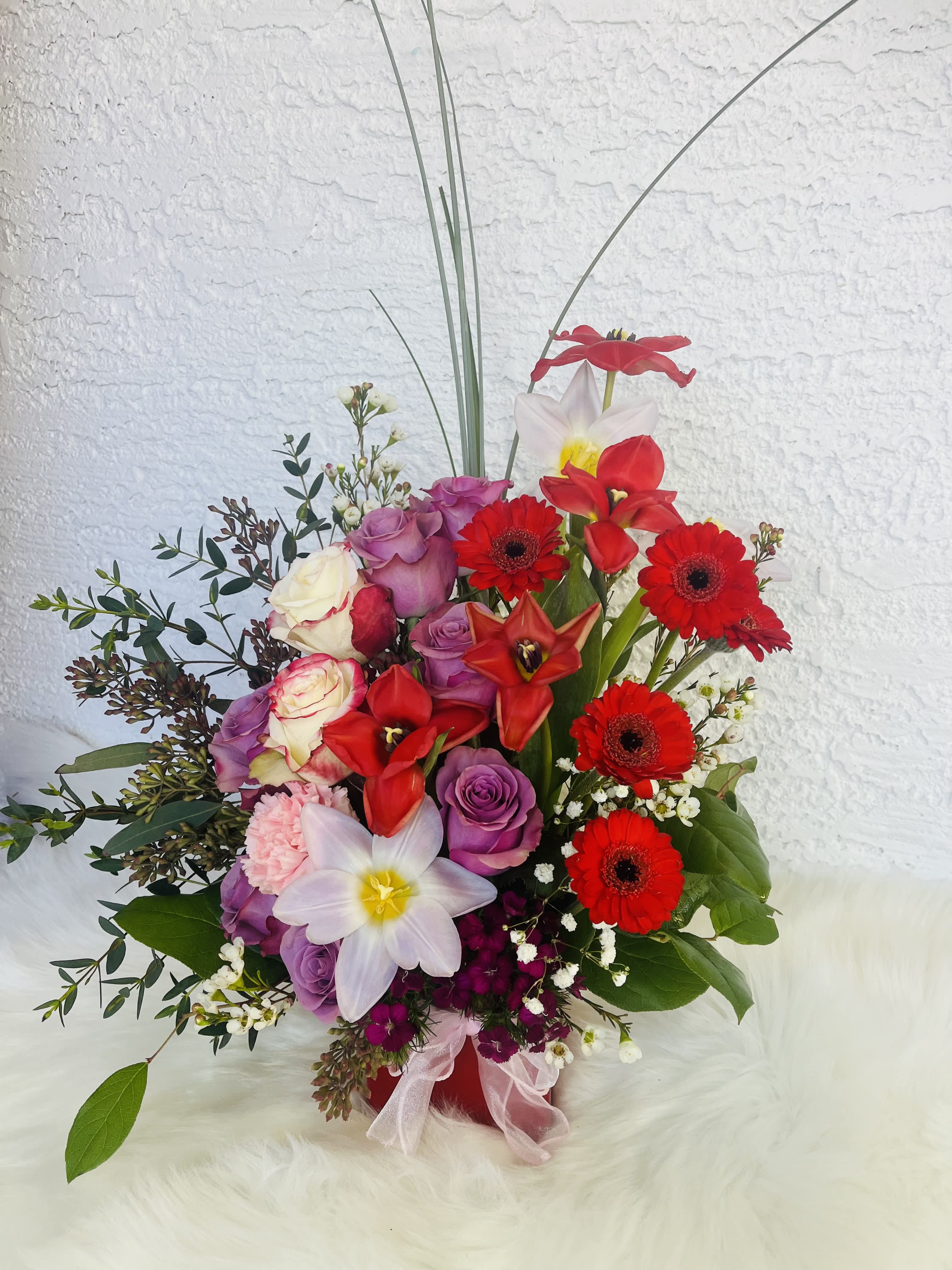Mixed bouquet with red gerberas, roses, and white daffodils in a red vase