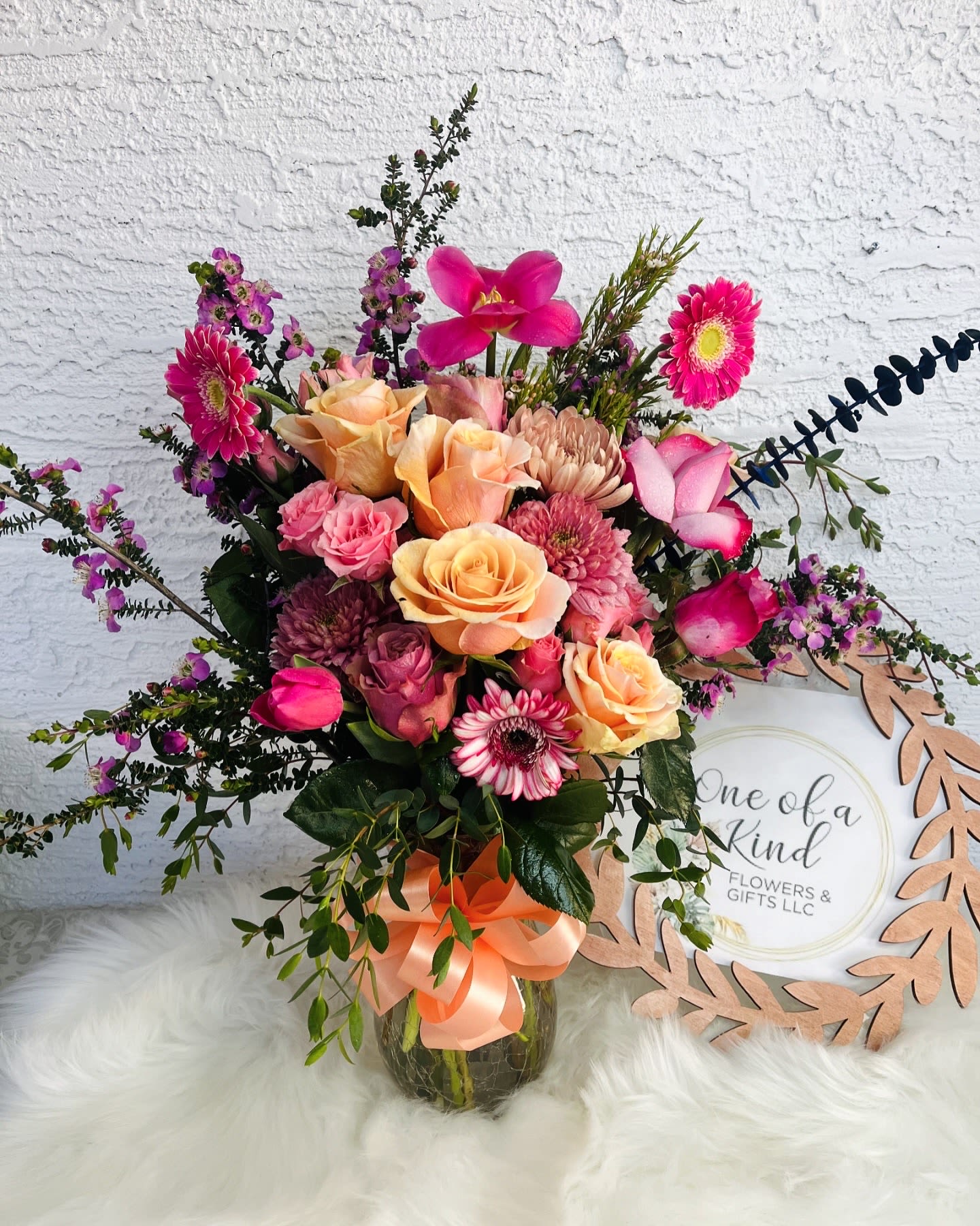 Mixed pink and peach flower bouquet in a glass vase with a ribbon