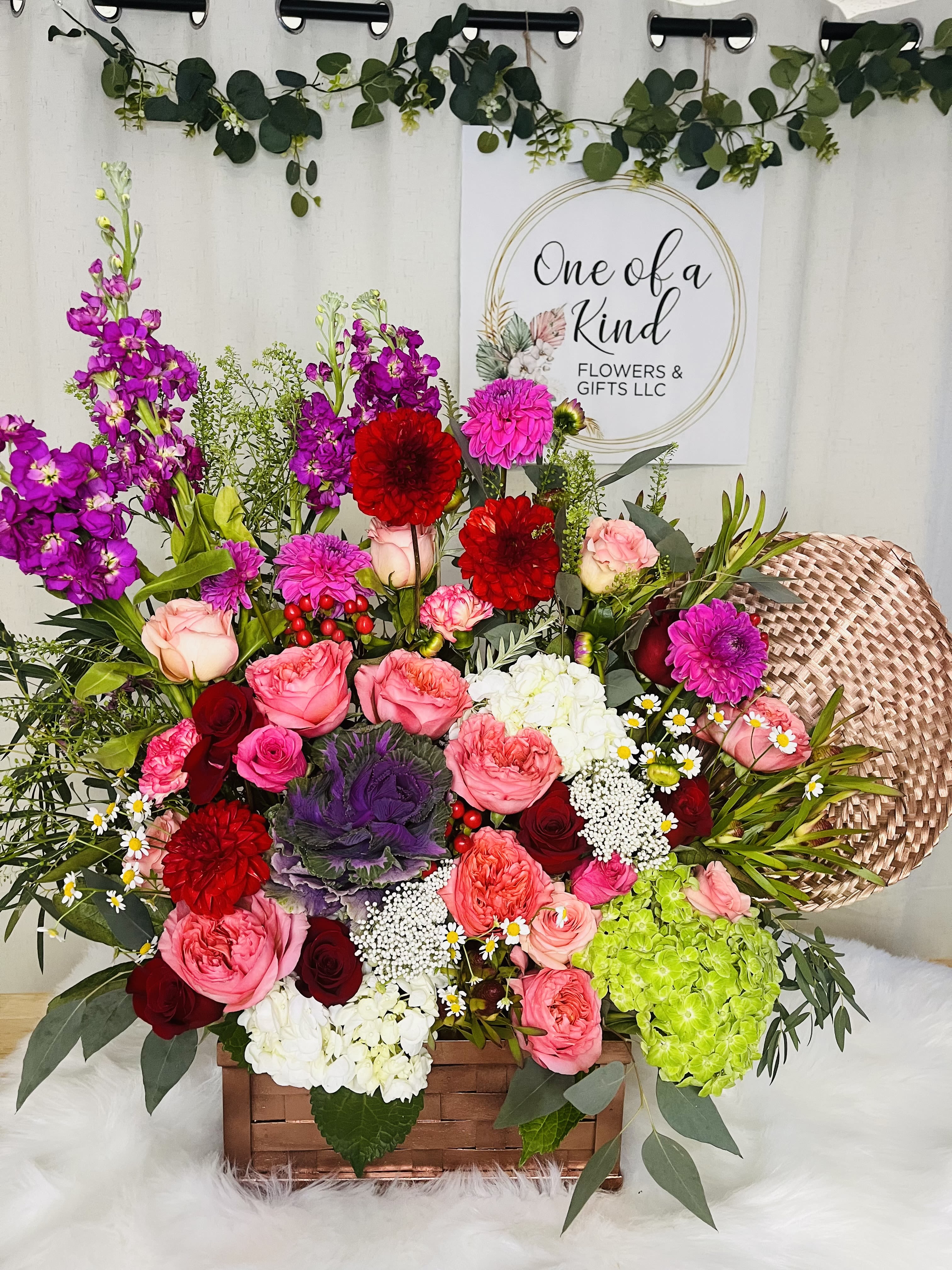 Mixed bouquet in a wooden basket with pink, red, purple, and white flowers