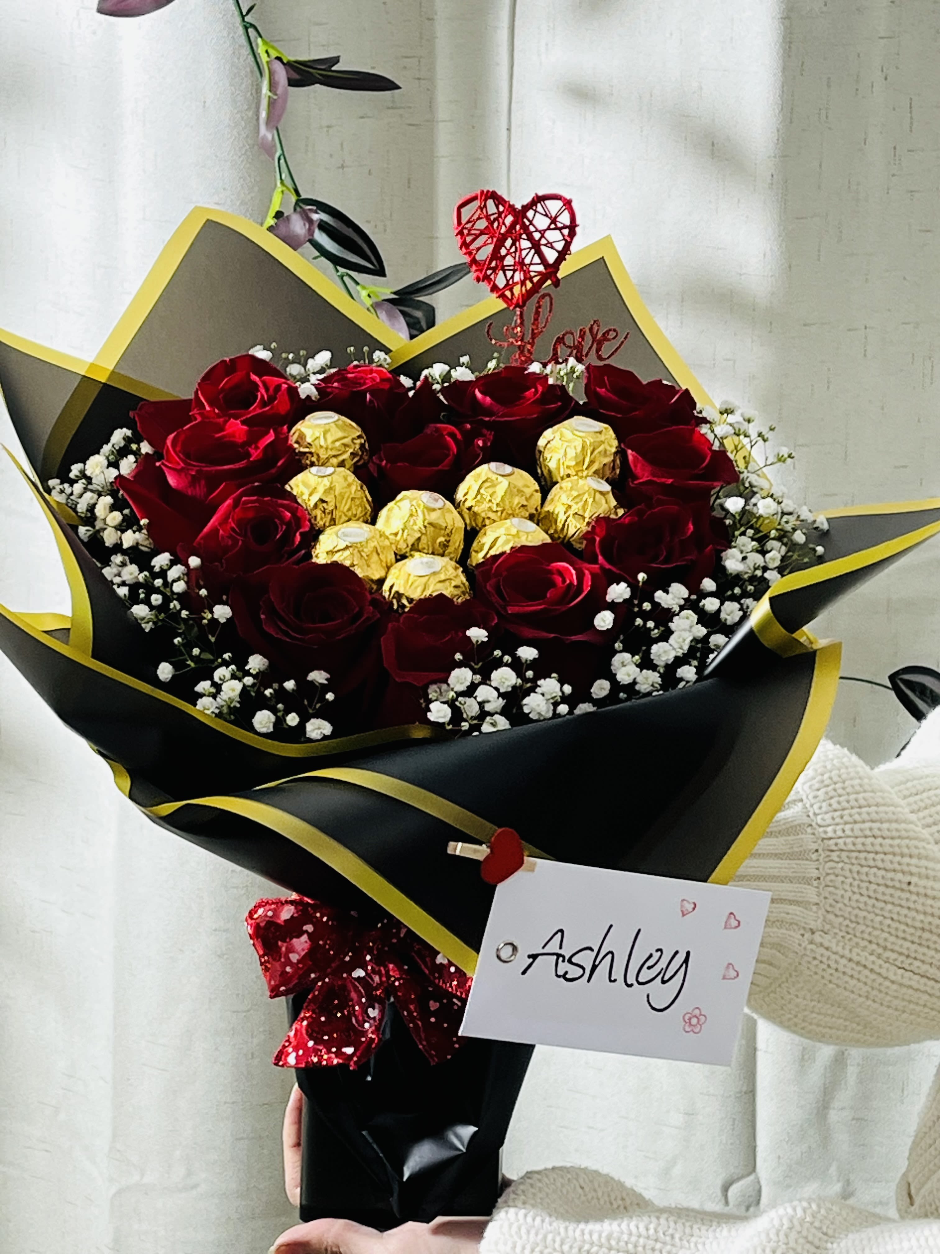 Bouquet of red roses with gold-wrapped chocolates and a heart topper